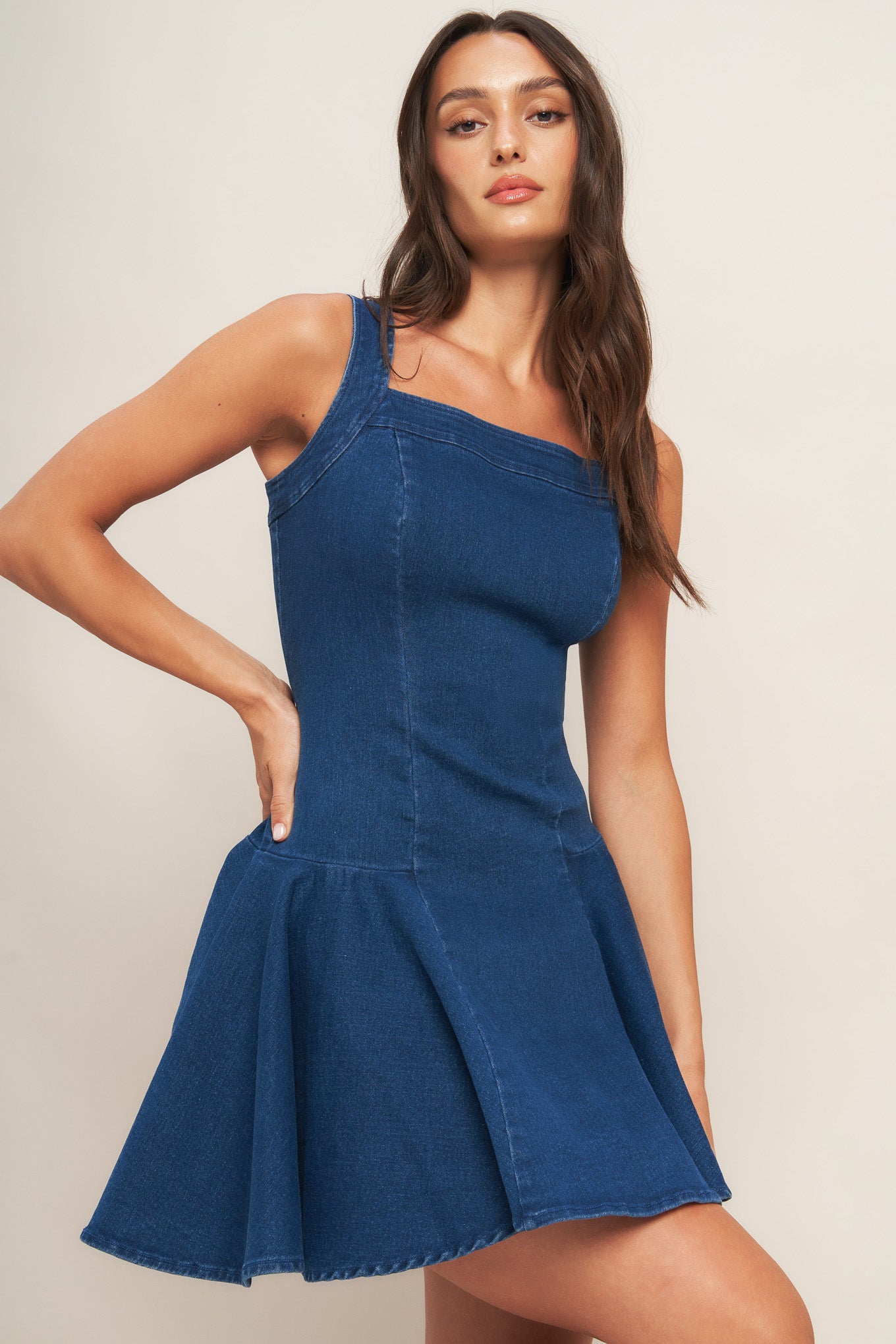 A washed denim mini dress featuring square neckline, sleeveless, body contouring with circle hem and back zipper closure