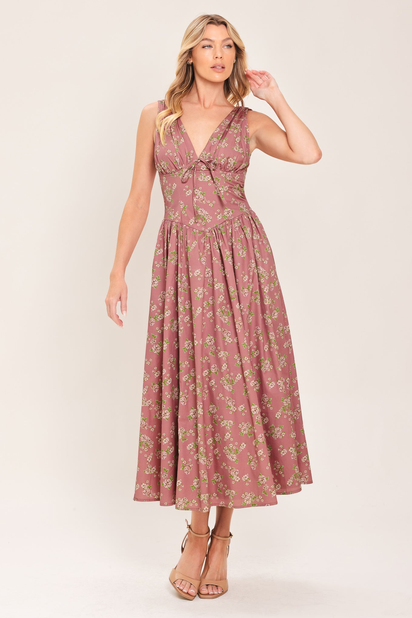 Woman wearing a mauve pink midi dress with small floral print and a woven featuring V neckline with bow tie, basque waistline, full skirt and back zipper closure | Flying Tomato