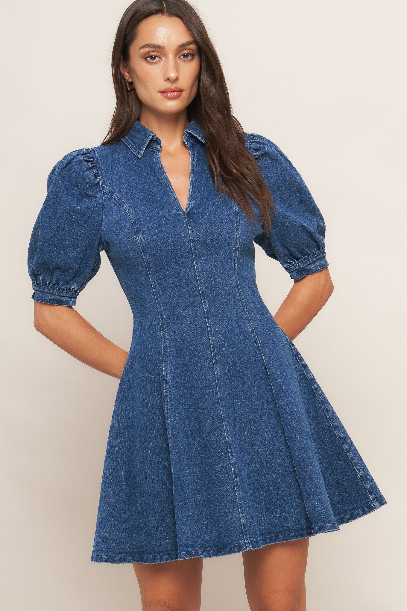 A washed denim mini dress featuring collar, front V, short puff sleeve, circle skirt and back zipper closure