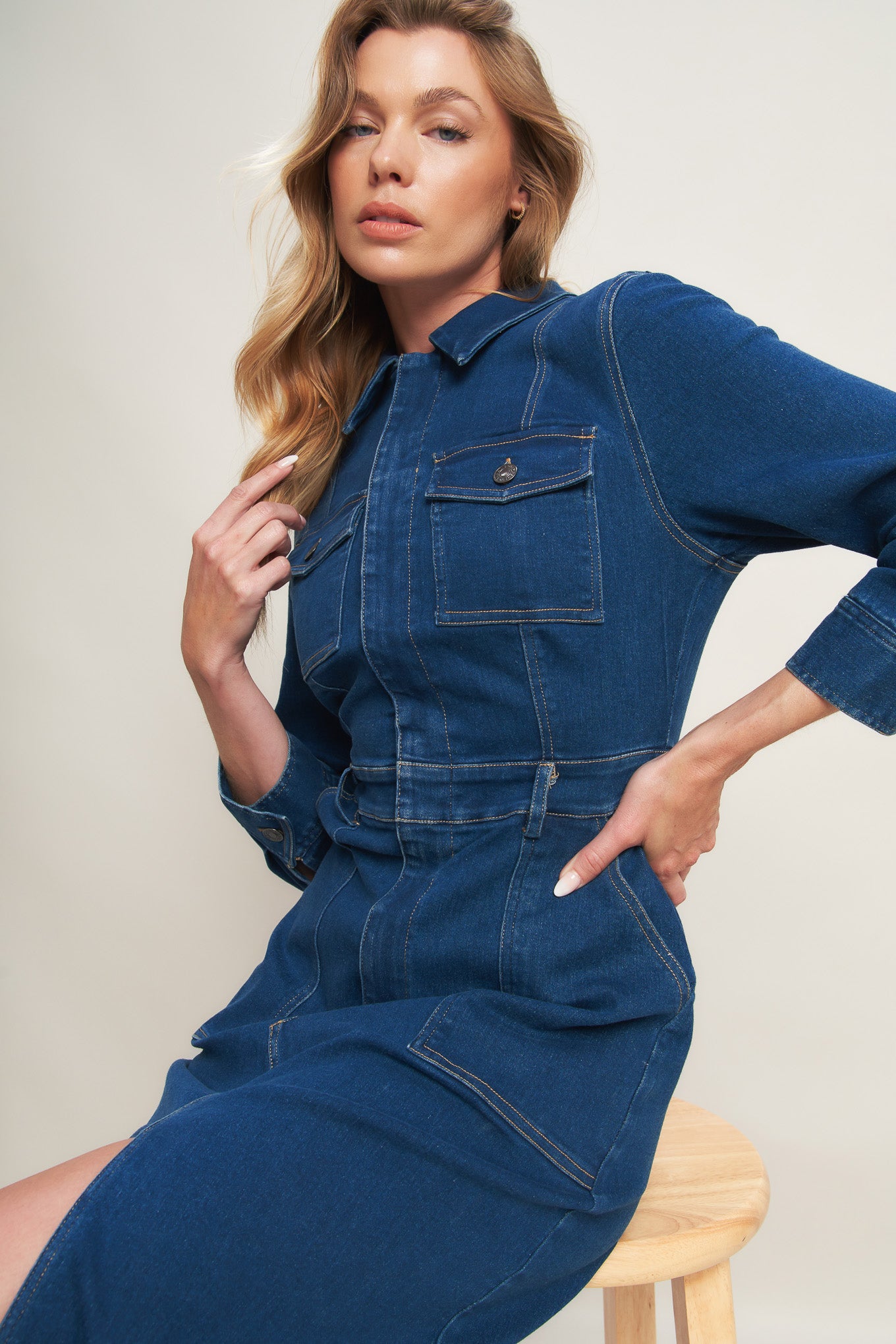A washed denim midi dress featuring collar, hidden front zipper closure, long sleeve, front and side pockets with bottom front slit