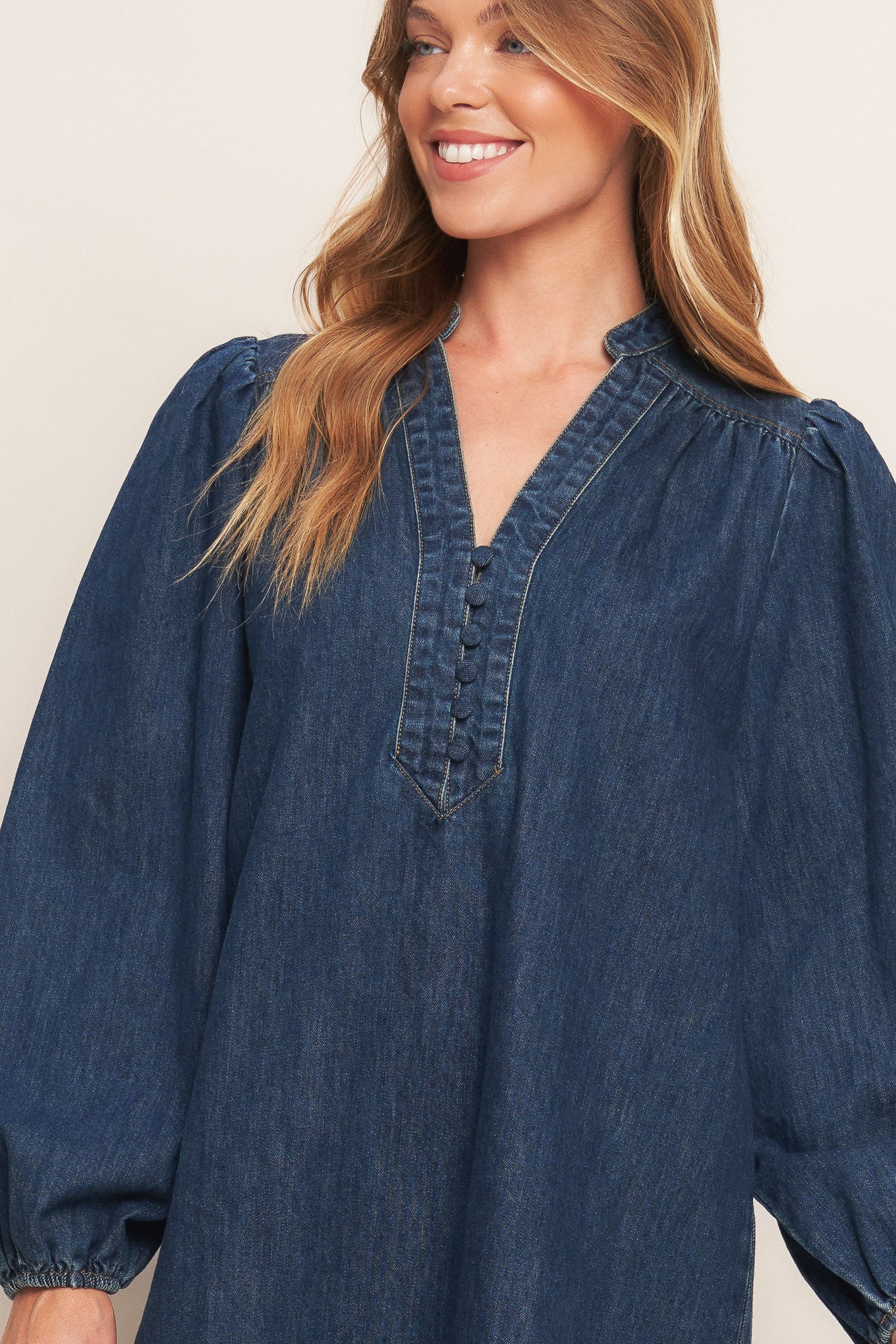 A washed denim mini dress featuring round neckline with V front, button down and long sleeve