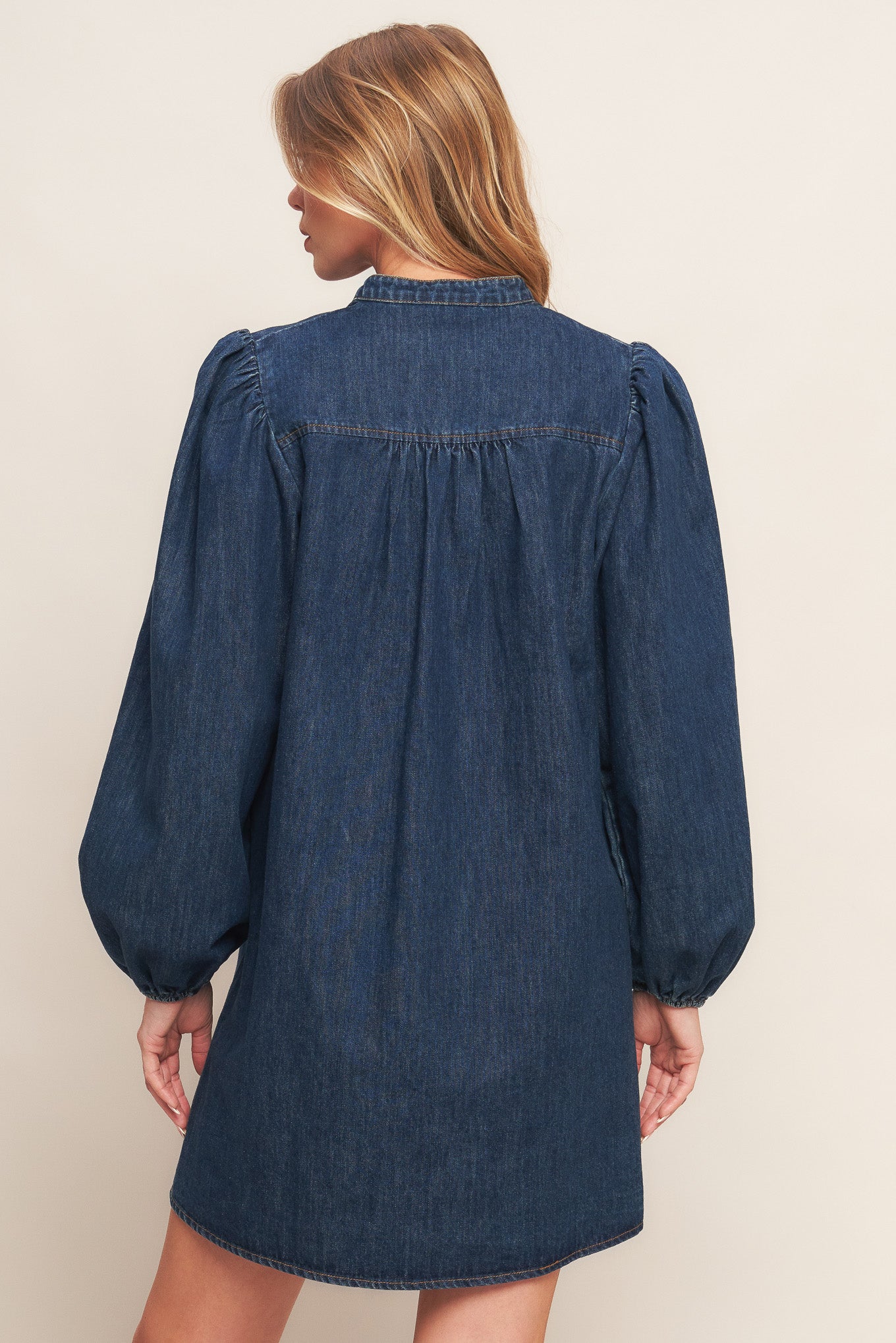 A washed denim mini dress featuring round neckline with V front, button down and long sleeve