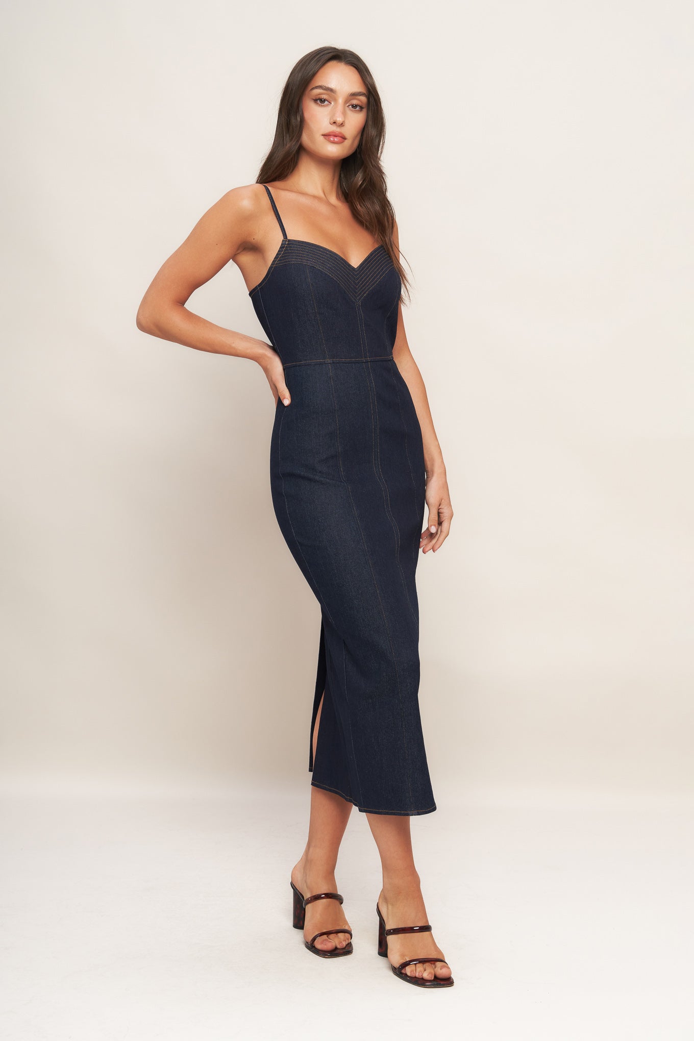 A denim midi dress featuring cami top with stitching detail, straps, pencil skirt and back zipper closure with slit