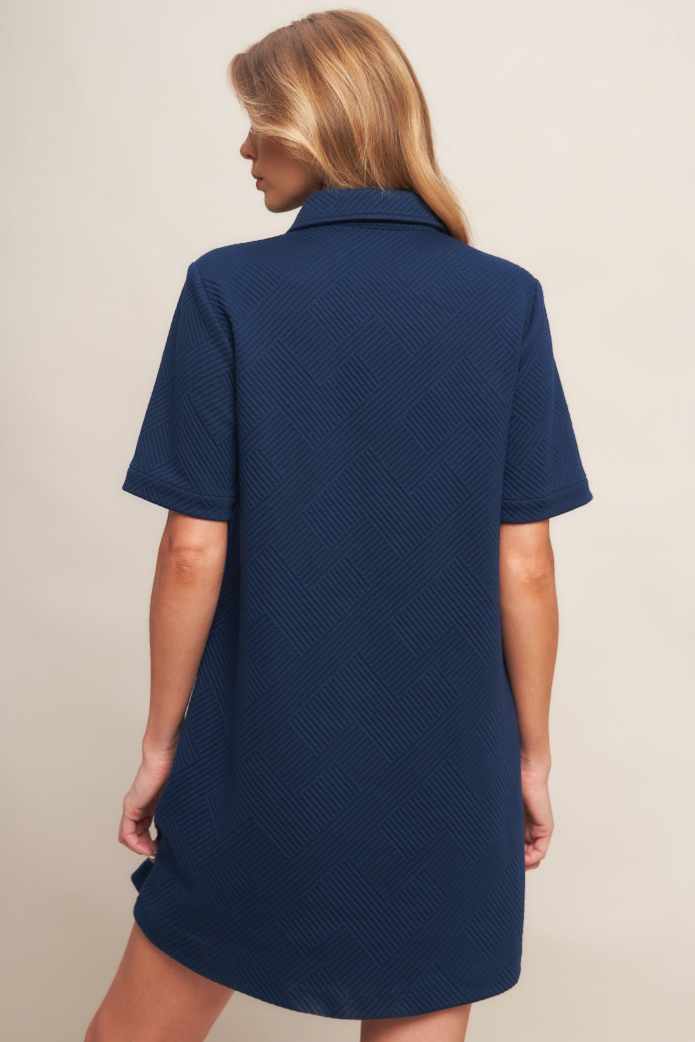 A textured knit mini dress featuring collar, front button down and short sleeve