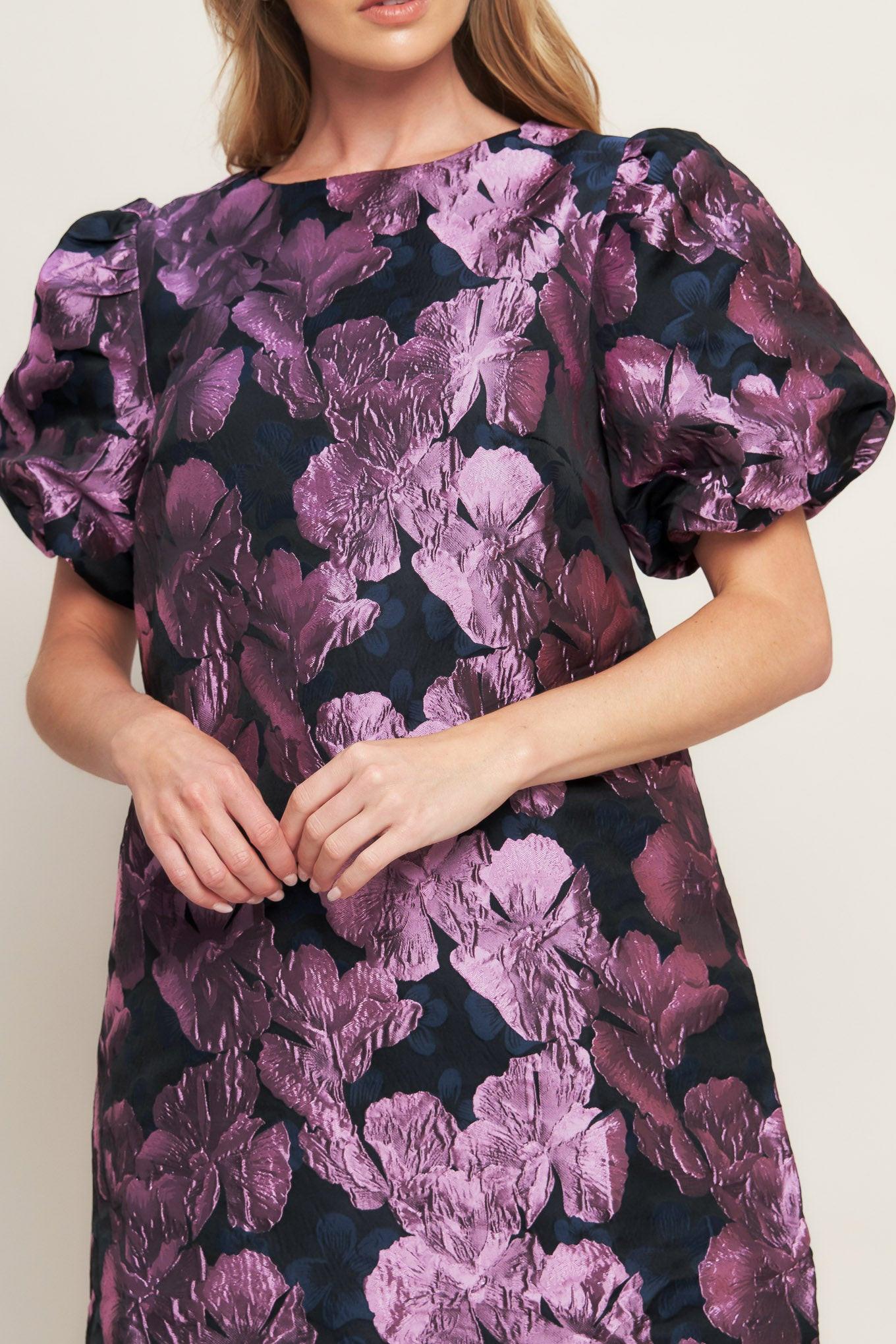 A textured woven mini dress featuring round neckline, short puff sleeve and back neck button closure