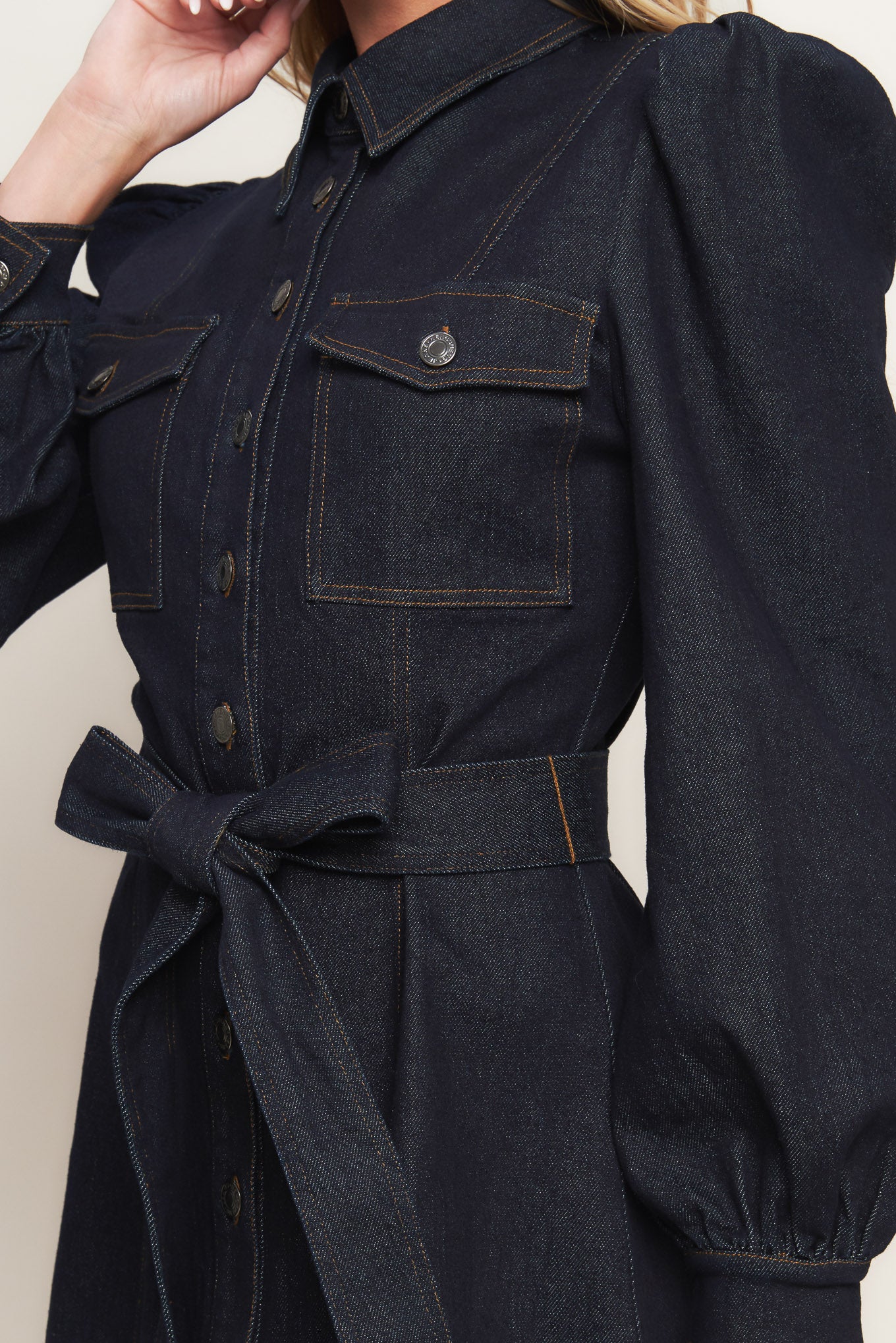A denim mini dress featuring collar, long sleeve, front pocket, button down closure and self sash tie
