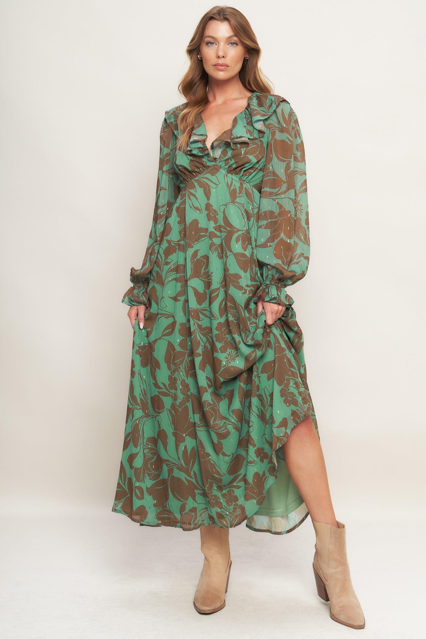 A printed woven maxi dress featuring V neckline with ruffles, empire waistline, long sleeve with ruffled cuff and elasticized back waist