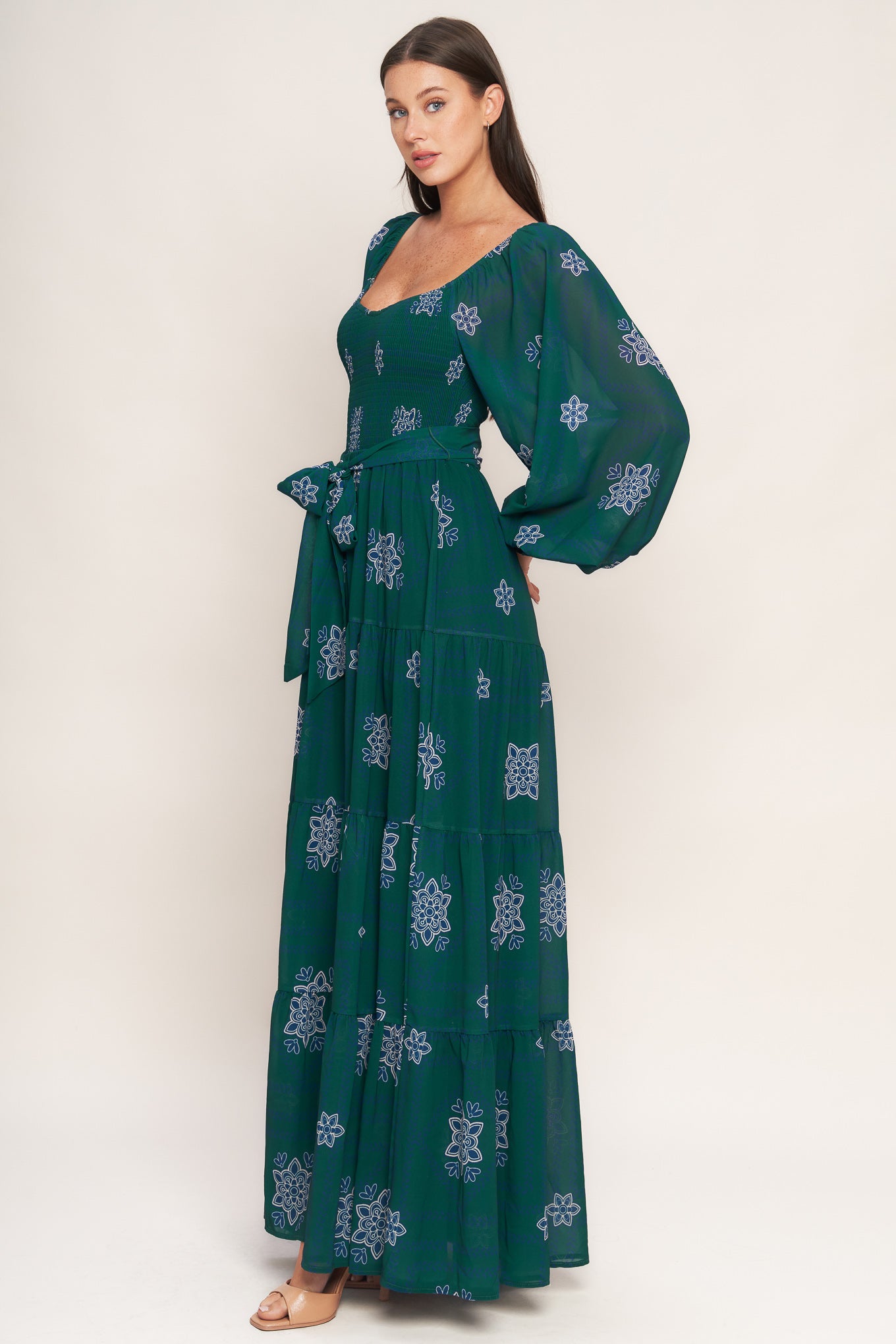 A printed woven maxi dress featuring sweetheart neckline, long sleeve with ruffled cuff, smocked bodice, tiered skirt and self sash tie