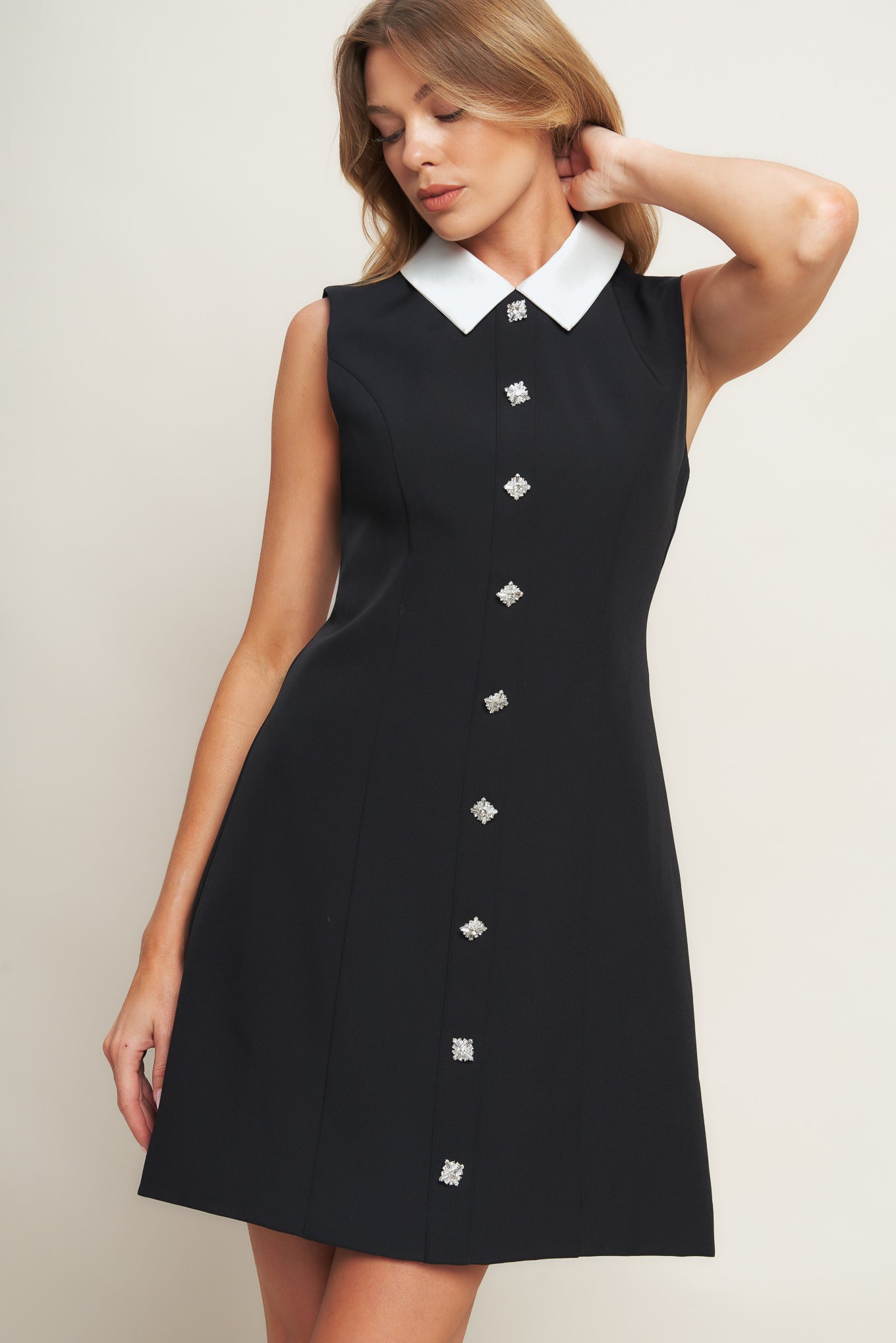A solid woven mini dress featuring collar, sleeveless, front button detail and back zipper closure