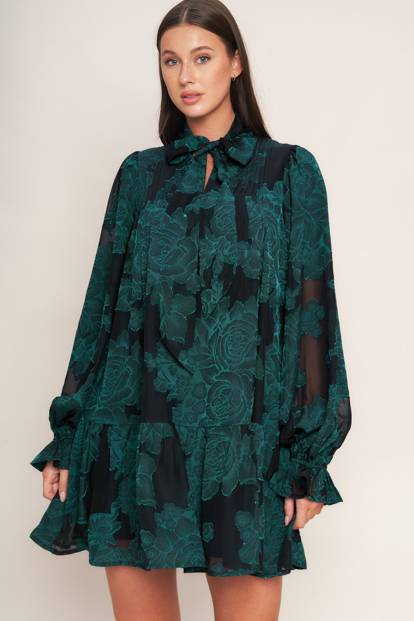 A burnout woven mini dress featuring front tie, long sleeve with ruffled cuff and ruffled hemline