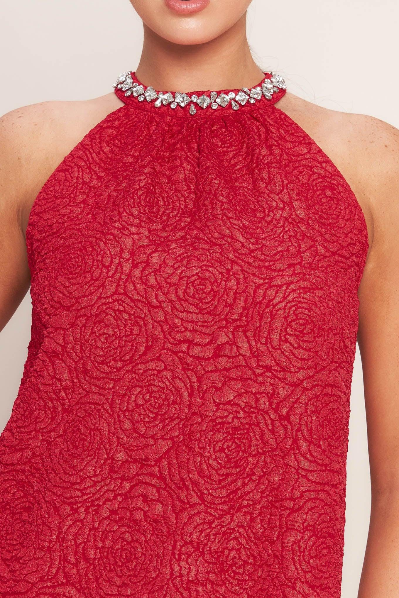 A textured woven mini dress featuring halter neckline with jewel embellishment, double ruffled hem and back neck button closure
