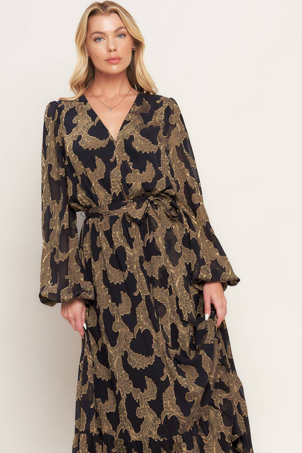 A woven jacquard maxi dress featuring surplice neckline, long sleeve, elasticized waist with self sash and ruffled hemline