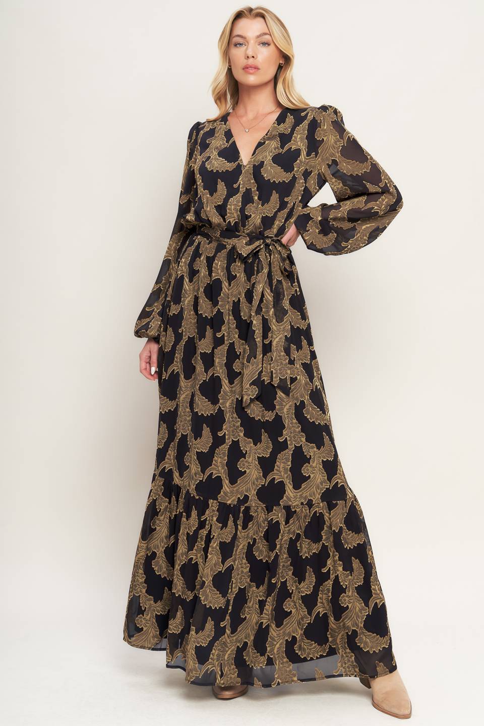 A woven jacquard maxi dress featuring surplice neckline, long sleeve, elasticized waist with self sash and ruffled hemline
