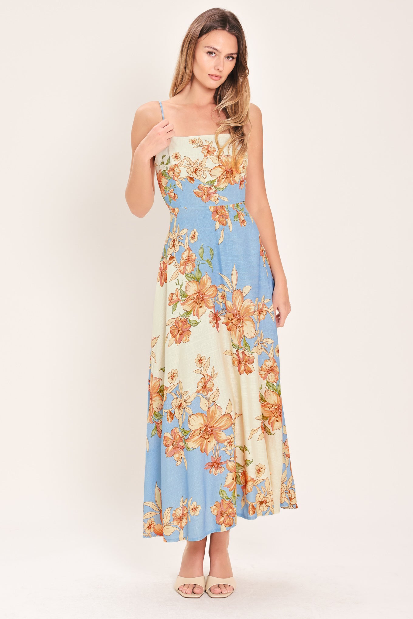 Woman wearing a blue and peach floral midi dress featuring straight neckline, straps, circle skirt and back zipper closure | Flying Tomato