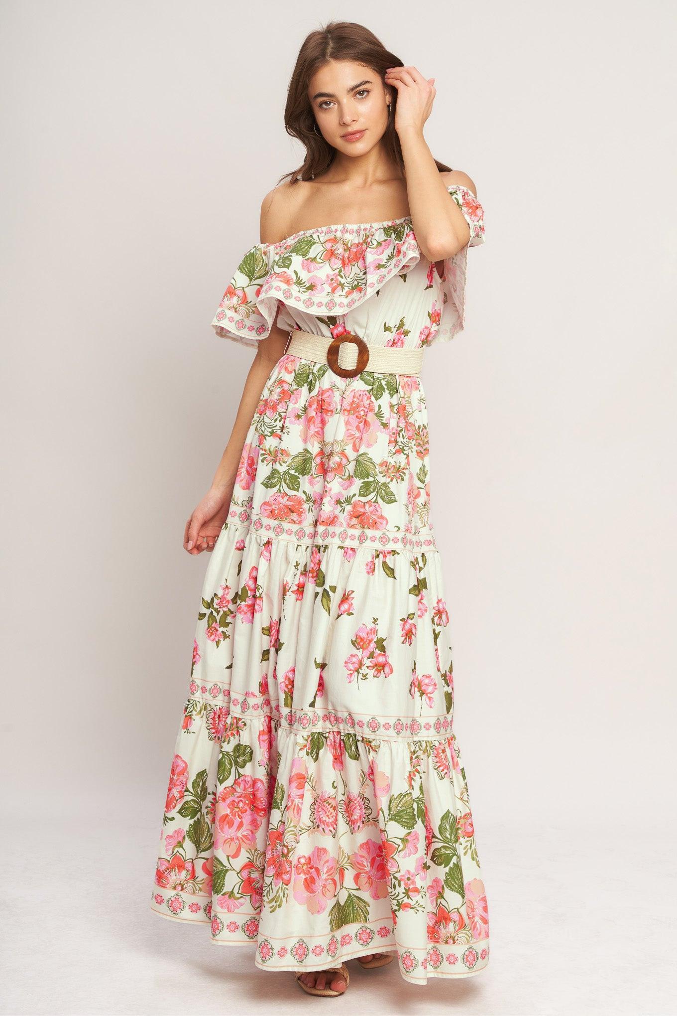 A printed maxi dress featuring off shoulder neckline with flounce, elasticized waist, contrasting belt and tiered skirt