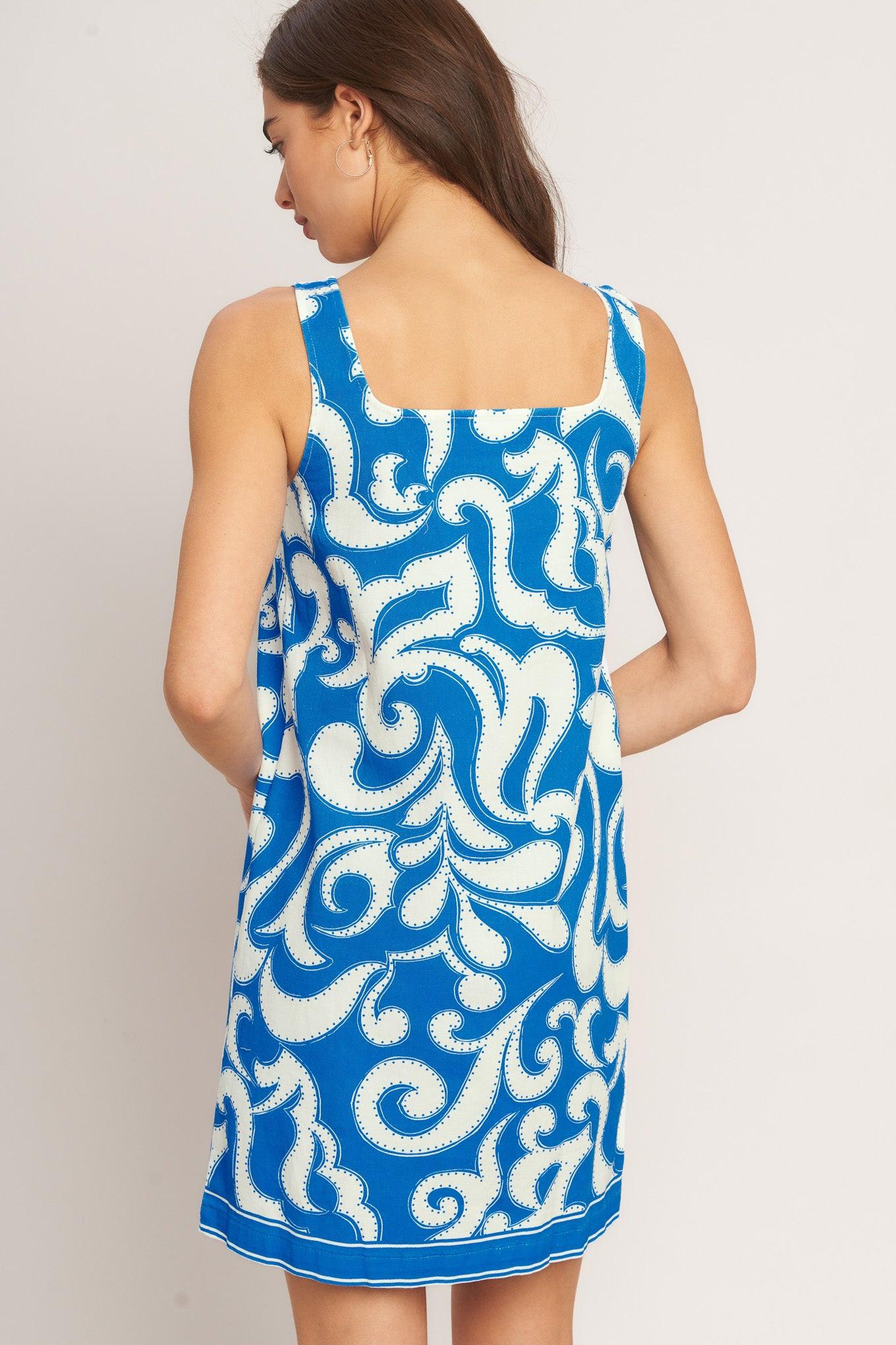 Woman wearing a blue and white patterned dress against a plain background