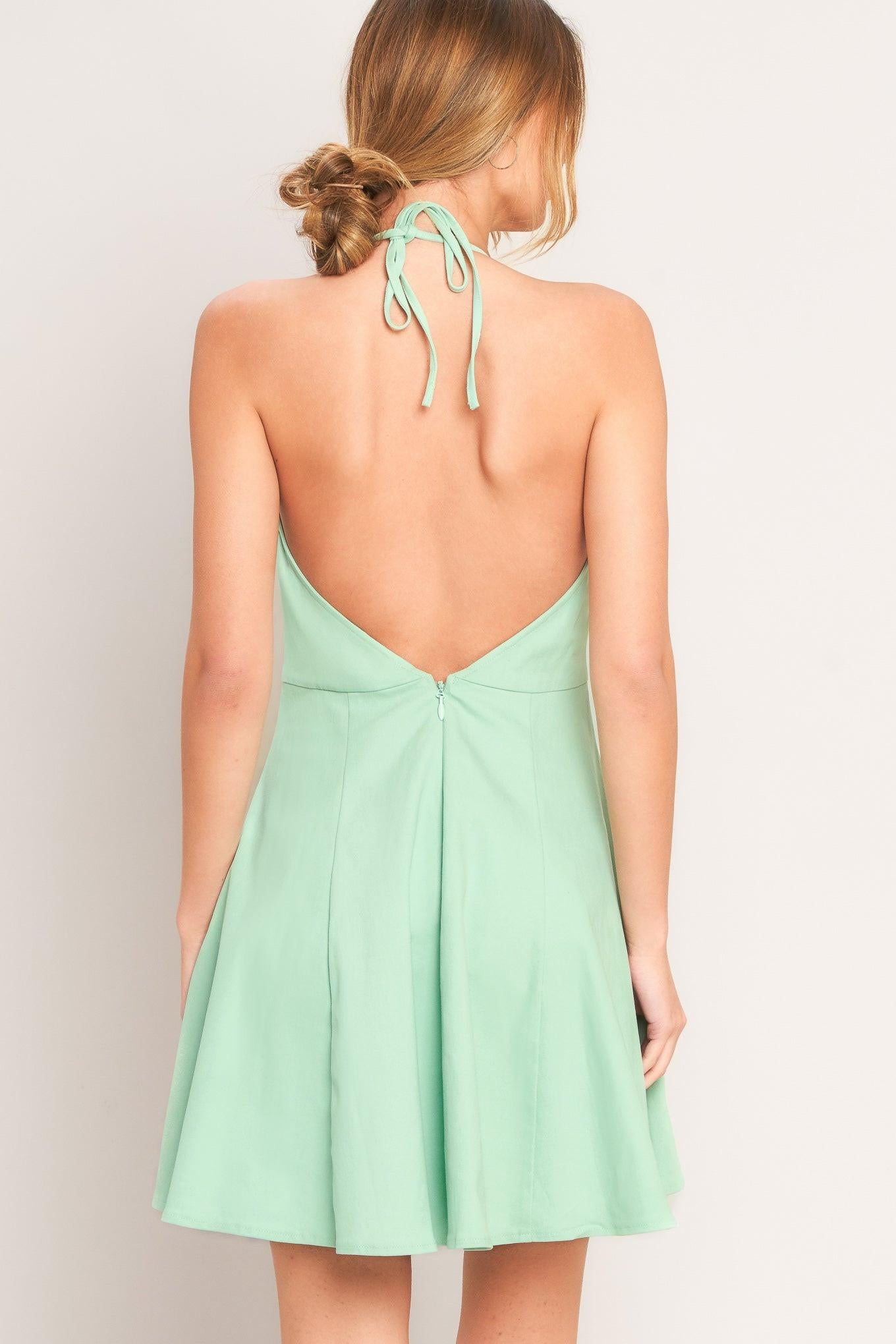 Mint green dress with open back on a plain background