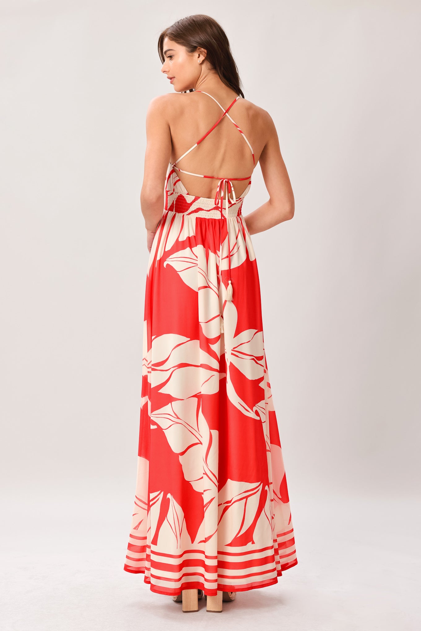 Woman wearing a red floral maxi dress featuring cami top, waist yoke, full skirt, bare back with tie and smocked waistband | Flying Tomato