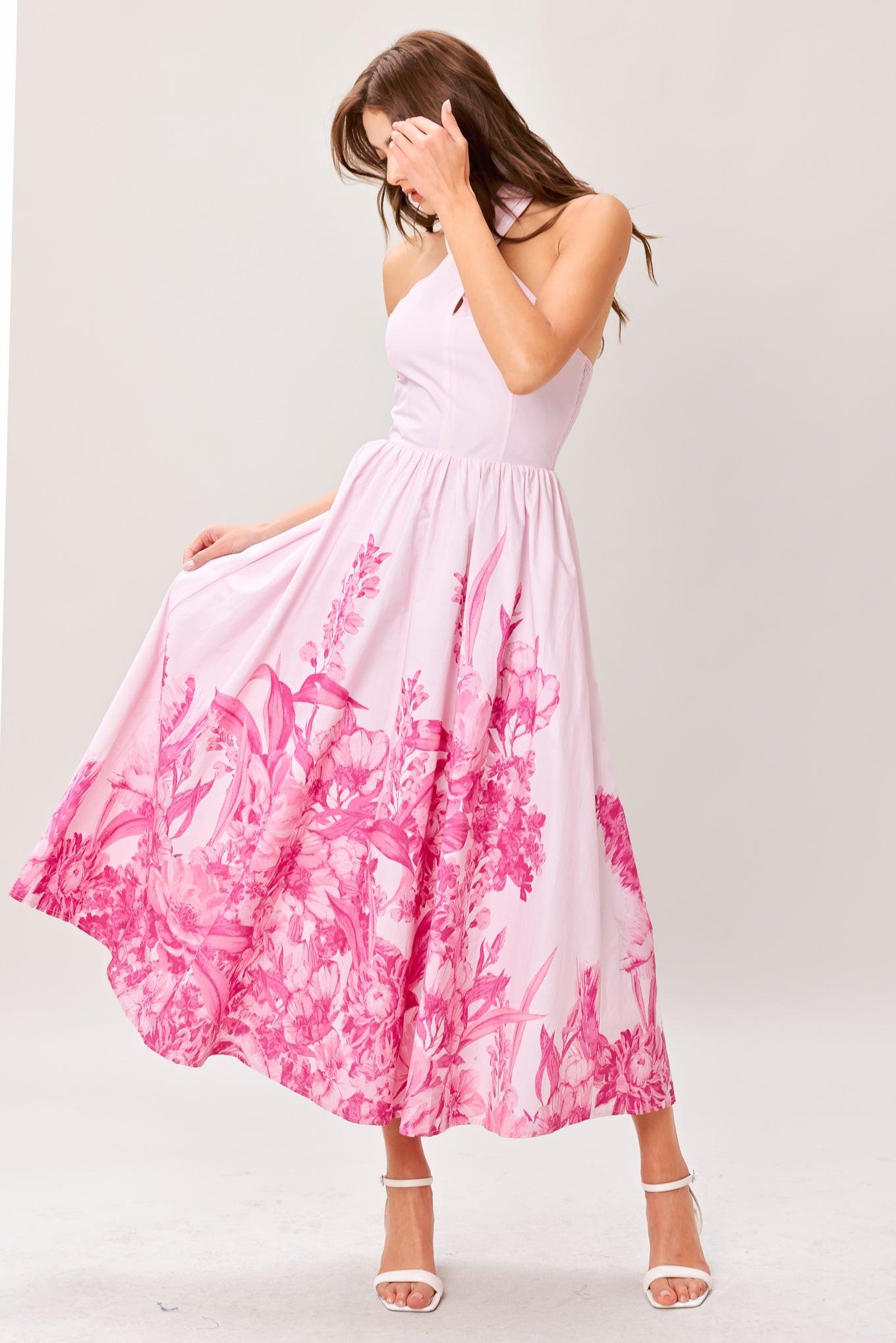 Woman wearing a pink floral printed woven midi dress featuring twist front with back neck tie, full skirt and smocked back bodice