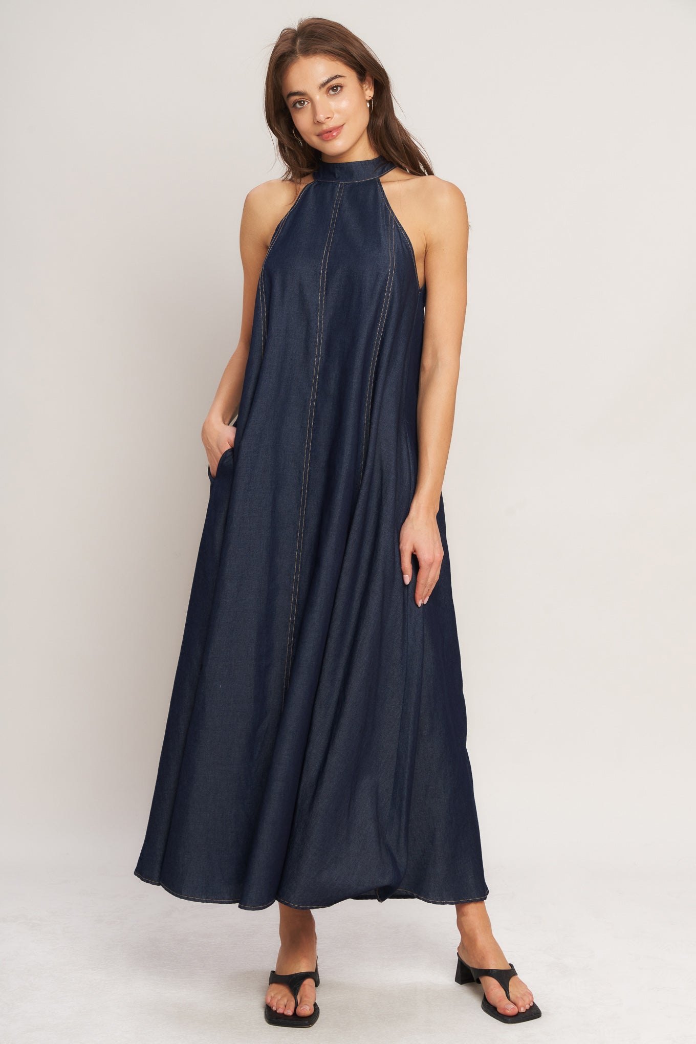 A solid woven midi halter dress with back neck button closure and side pockets