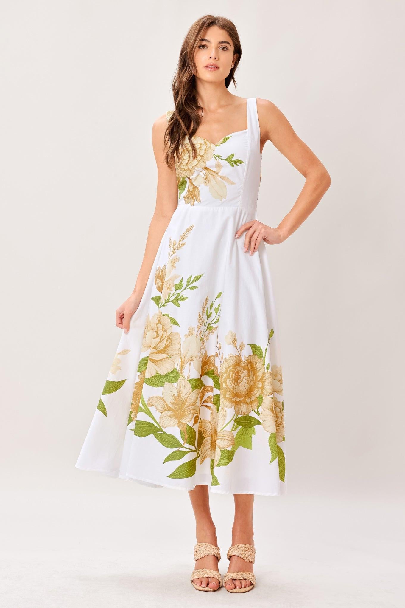 Woman wearing a white dress with yellow floral patterns on a white background