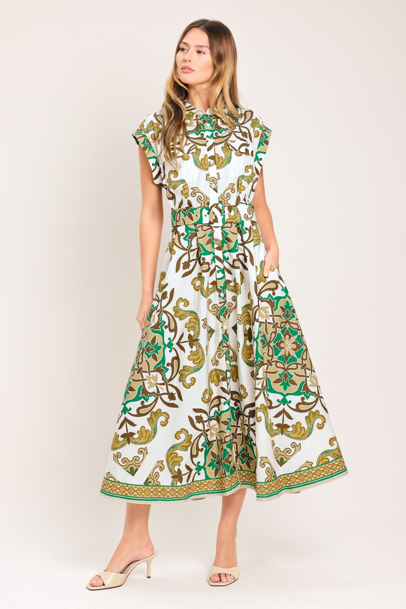 Woman wearing a green, brown, and white patterned midi shirt dress featuring cuffed short sleeve, front button down, self belt and side pockets | Flying Tomato