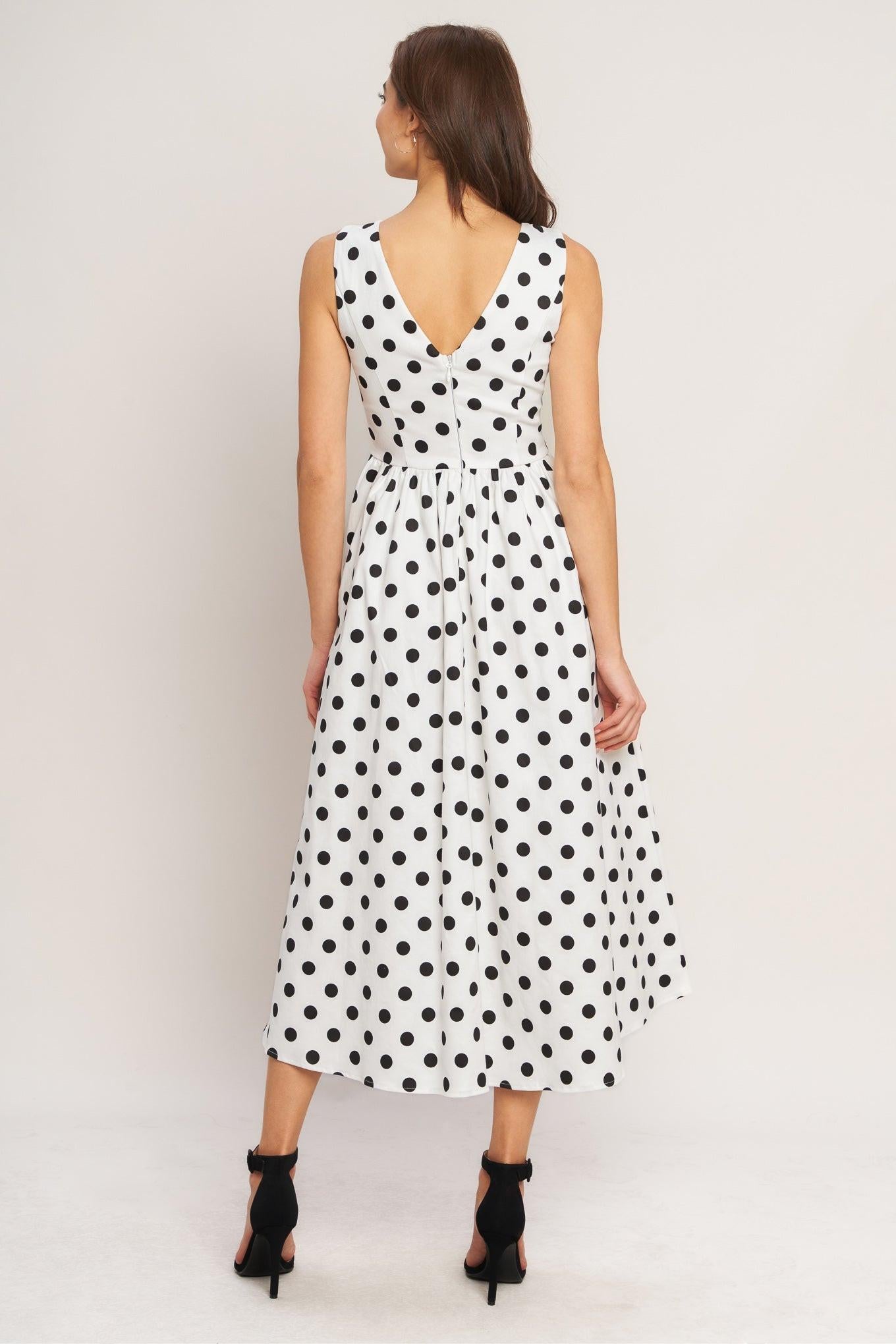 Woman wearing a black and white polka dot dress on a plain background