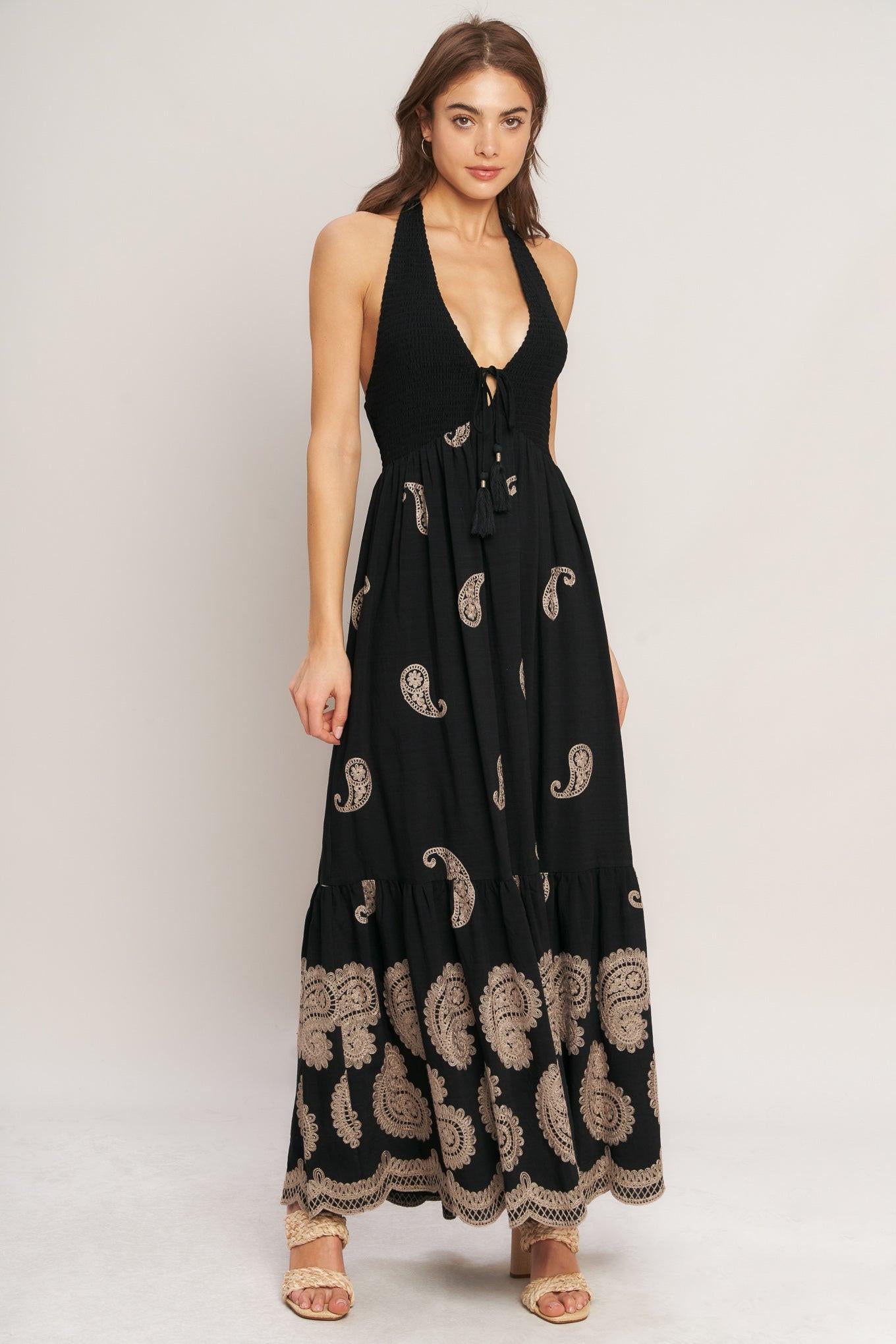 An embroidered woven midi dress featuring halter neckline, smocked bodice with front tie and bare back with back neck tie closure