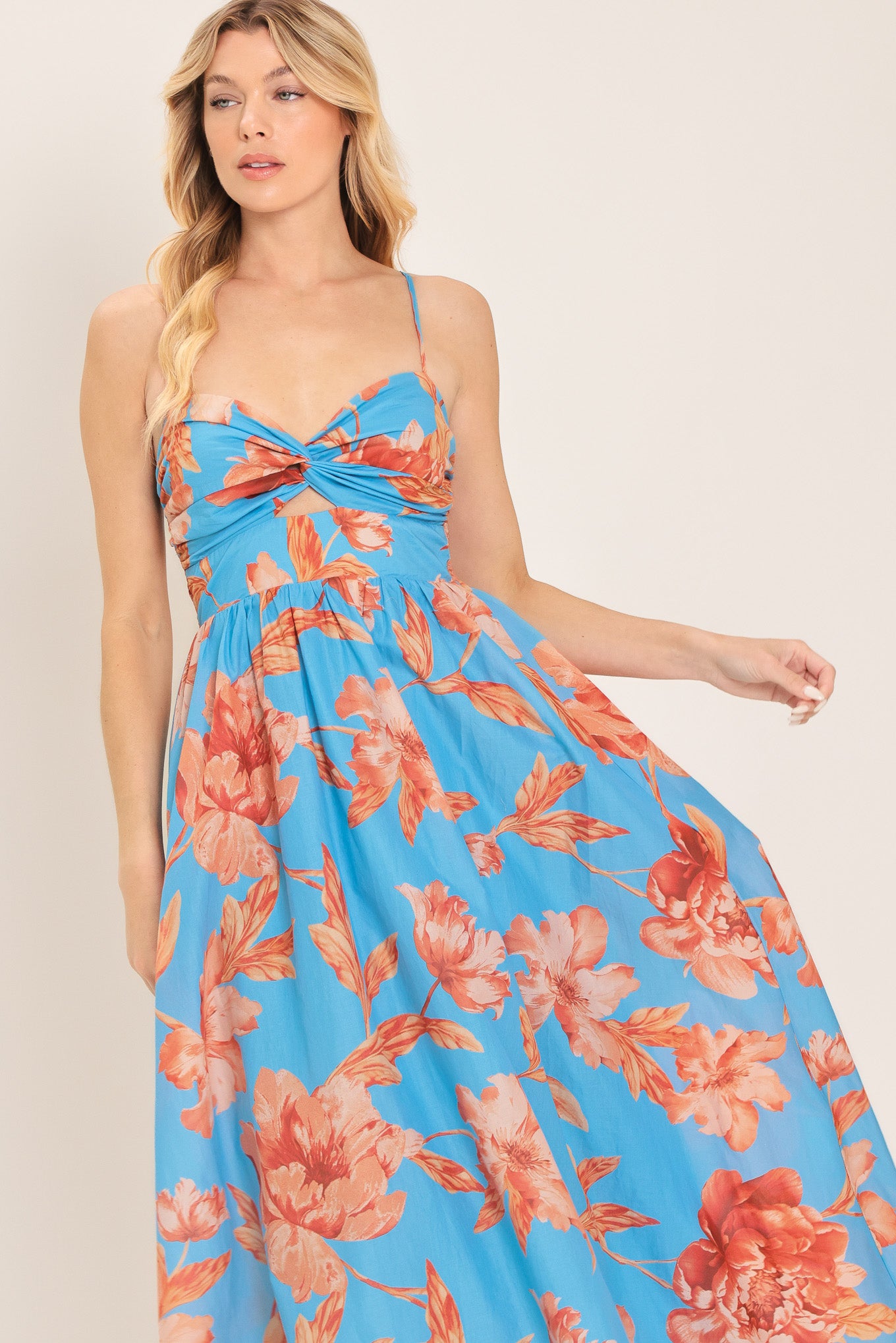 Woman wearing a blue with peach floral pattern midi dress featuring twisted bodice with cut out, straps, full skirt and smocked back bodice | Flying Tomato