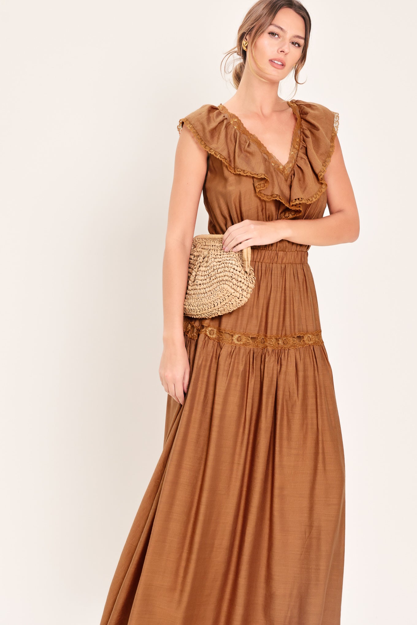 Woman wearing a brown maxi dress featuring V neckline with ruffle and lace edge, elastic waist and back tie | Flying Tomato
