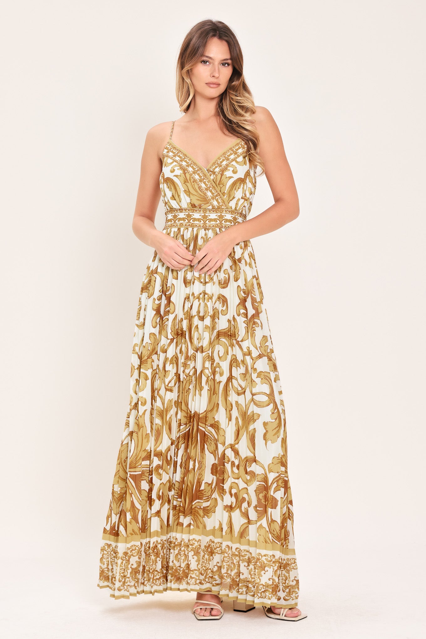Woman wearing a gold and white baroque patterned maxi dress featuring surplice neckline, straps, pleated skirt and smocked back waistband | FLYING TOMATO