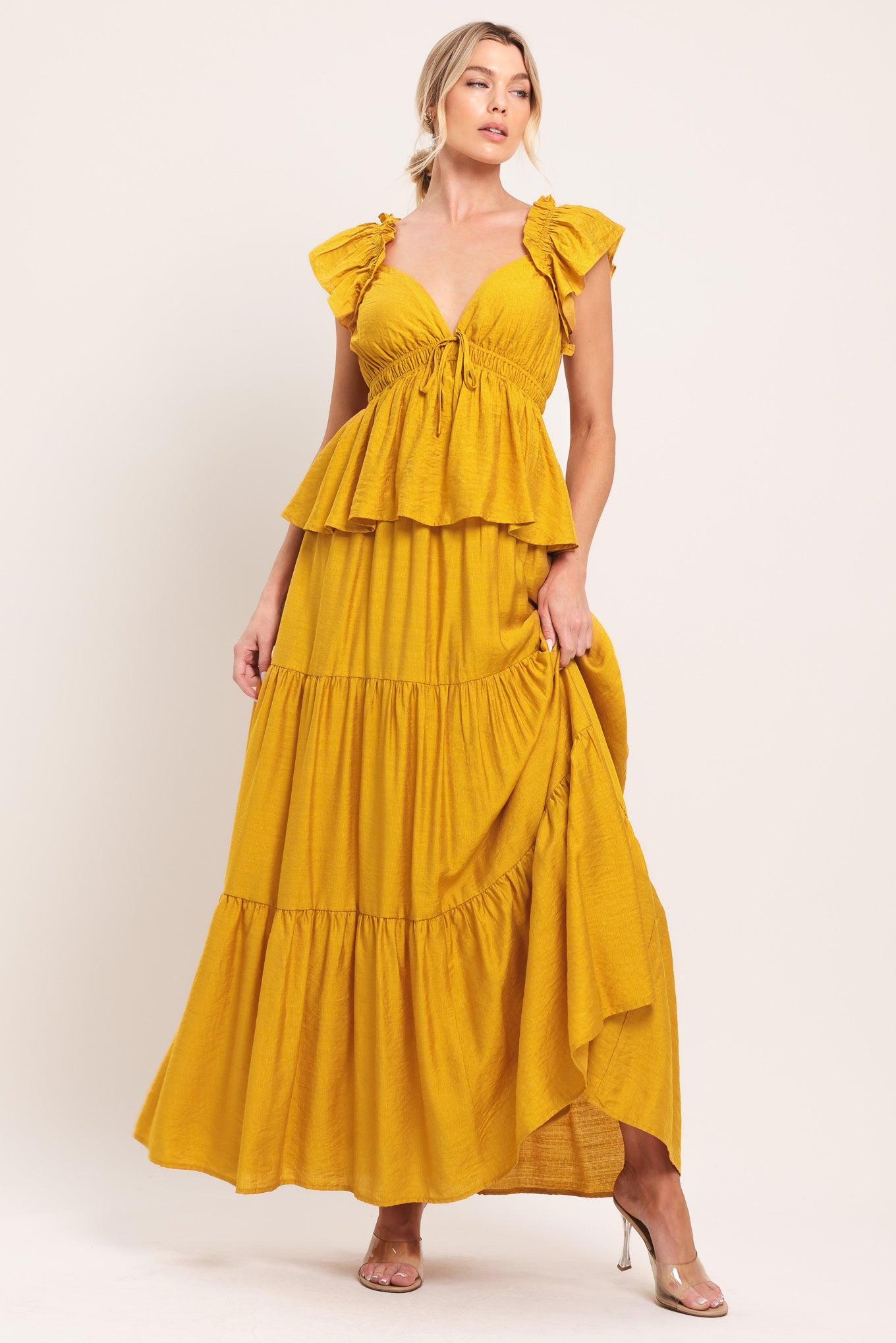 Woman wearing a mustard yellow tiered maxi dress featuring sweetheart neckline, short ruffle sleeve, and elastic empire | Flying Tomato