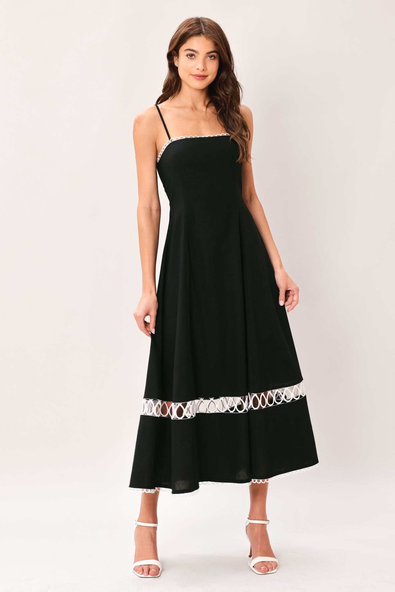 Woman wearing a black midi dress featuring straight neckline with lace edge trim, straps, circle skirt with lace inset bottom, lace edge trim and back zipper closure | Flying Tomato