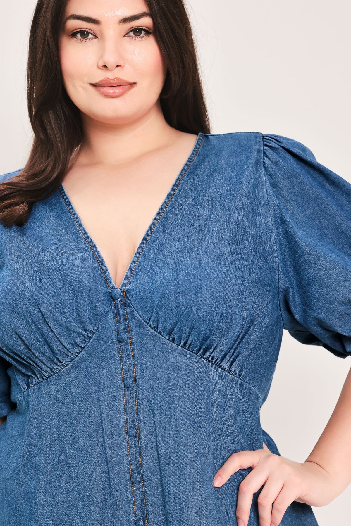 Woman wearing a denim mini dress featuring V neckline, short puff sleeve, button down detail, circle skirt and back zipper closure | Flying Tomato