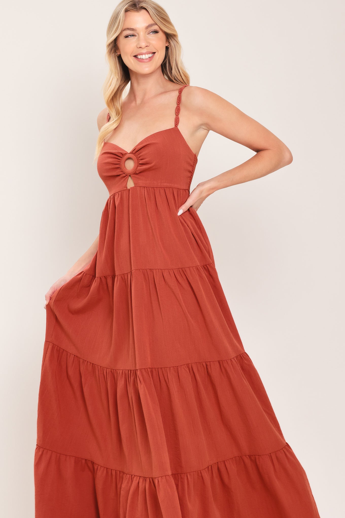 Woman wearing a rust-colored tiered maxi dress featuring cami top with O ring and cut out, lace straps, and smocked back bodice | Flying Tomato