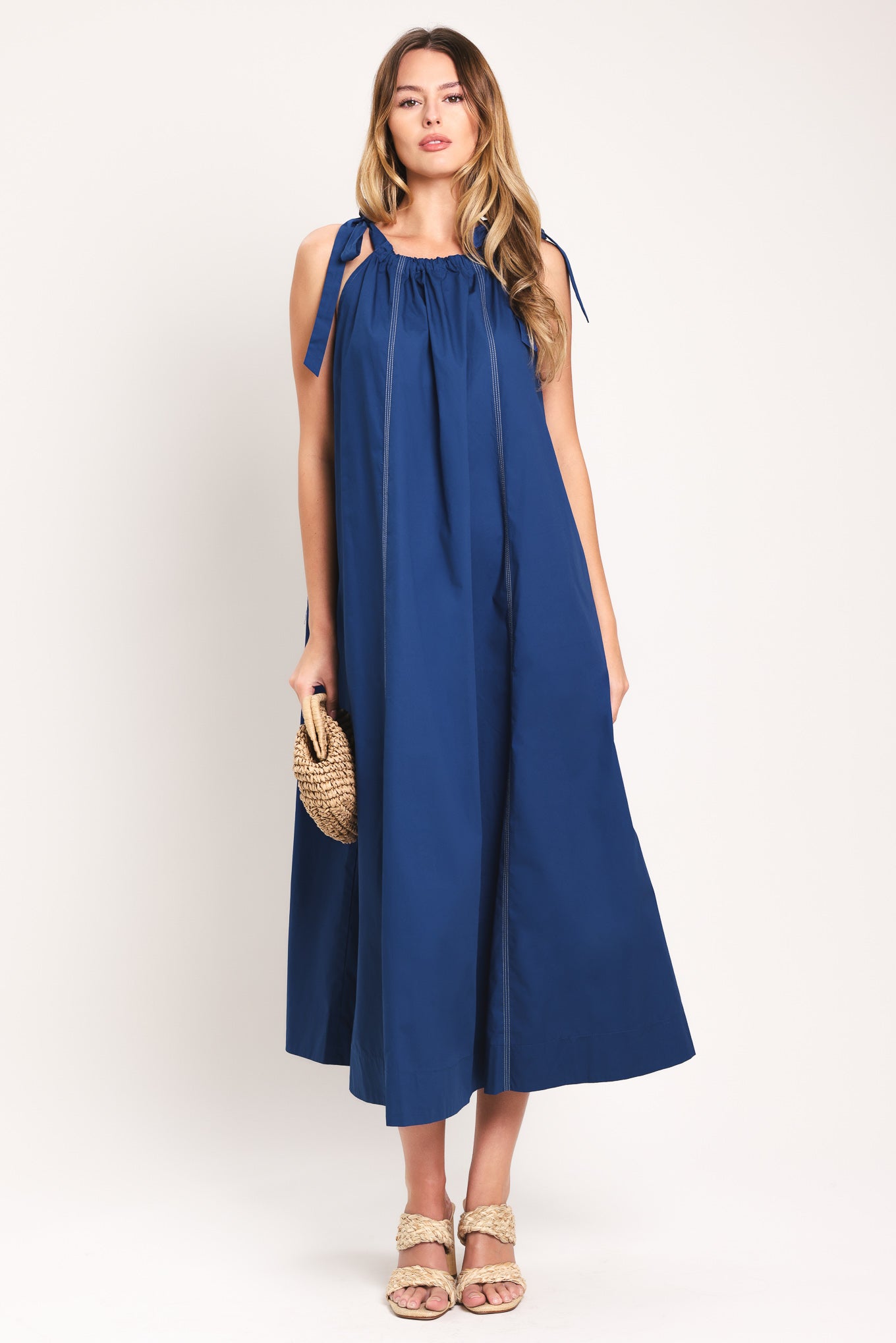 Woman wearing a blue midi dress with bow straps and pockets | Flying Tomato