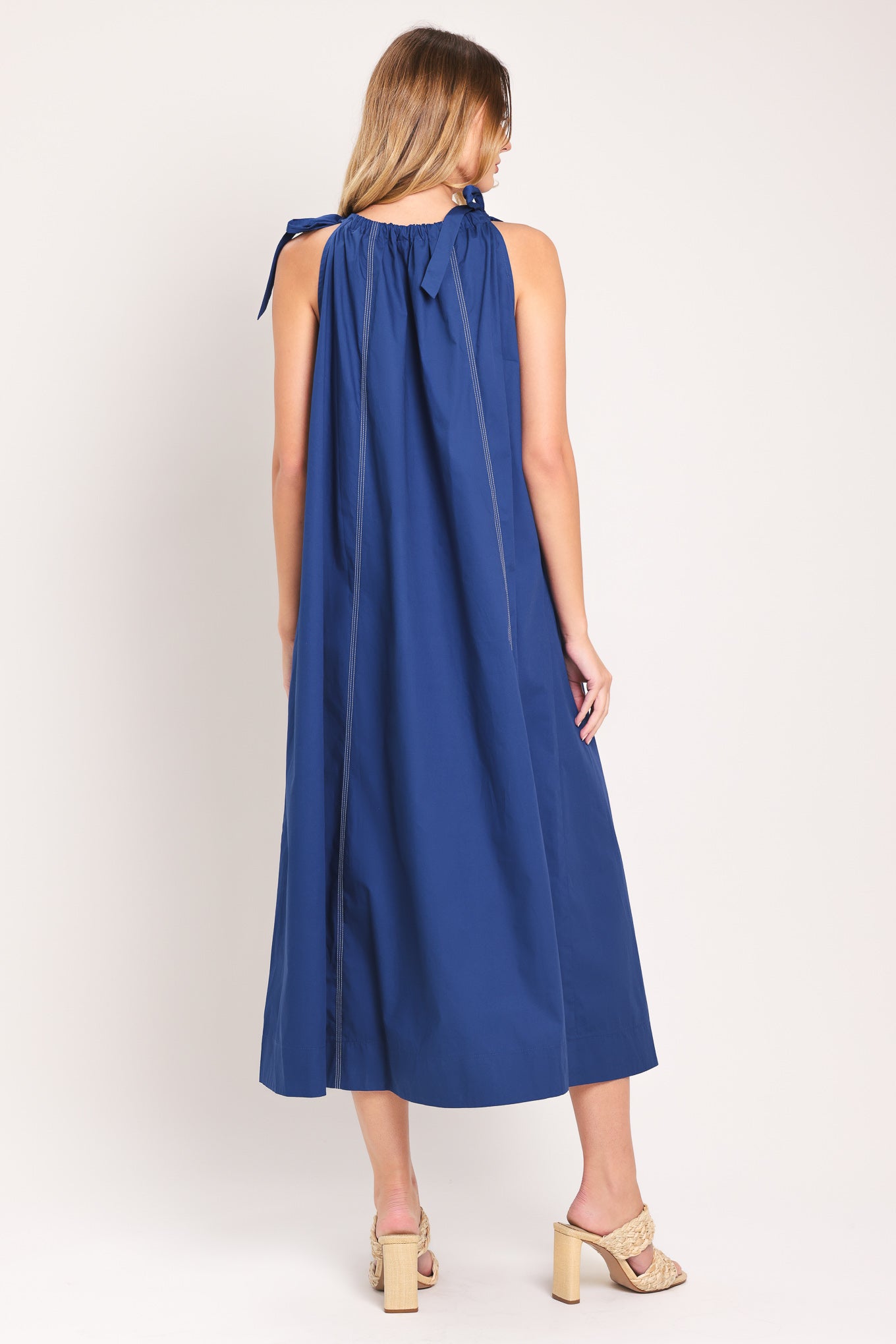 Woman wearing a blue midi dress with bow straps and pockets | Flying Tomato