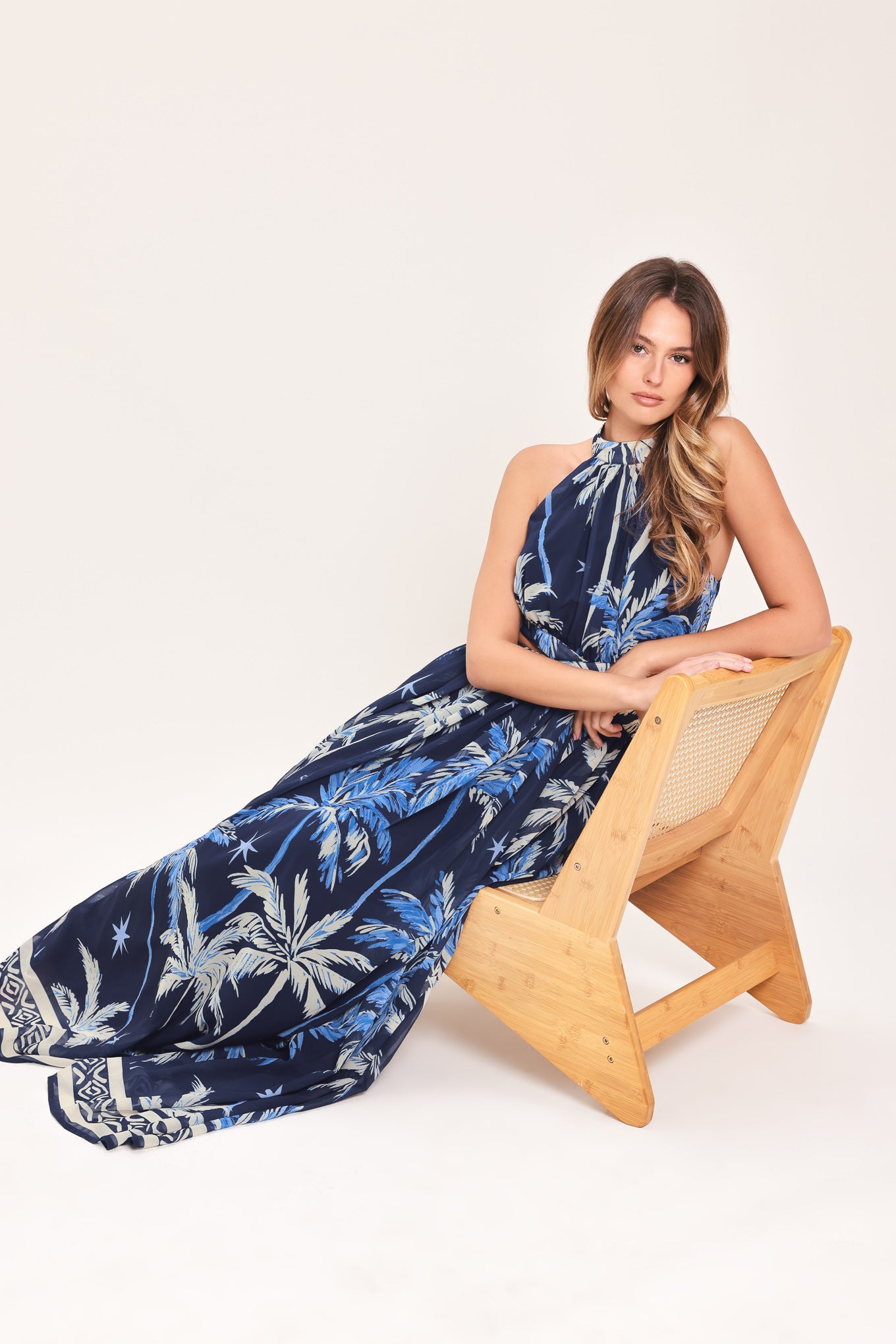 Woman wearing a blue and navy tropical patterned dress with palm trees | Flying Tomato