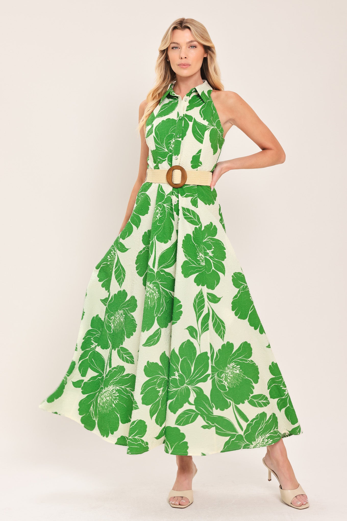 Woman wearing a sleeveless green floral midi dress featuring collar, front button down, contrasting belt and full skirt | Flying Tomato