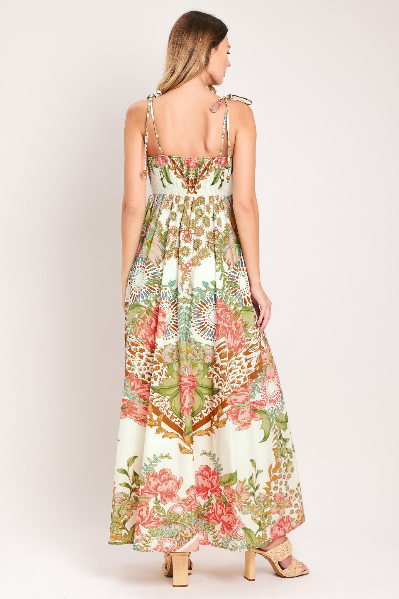 Woman wearing a floral ankle dress featuring straight neckline with shoulder tie, full skirt and smocked back bodice | Flying Tomato
