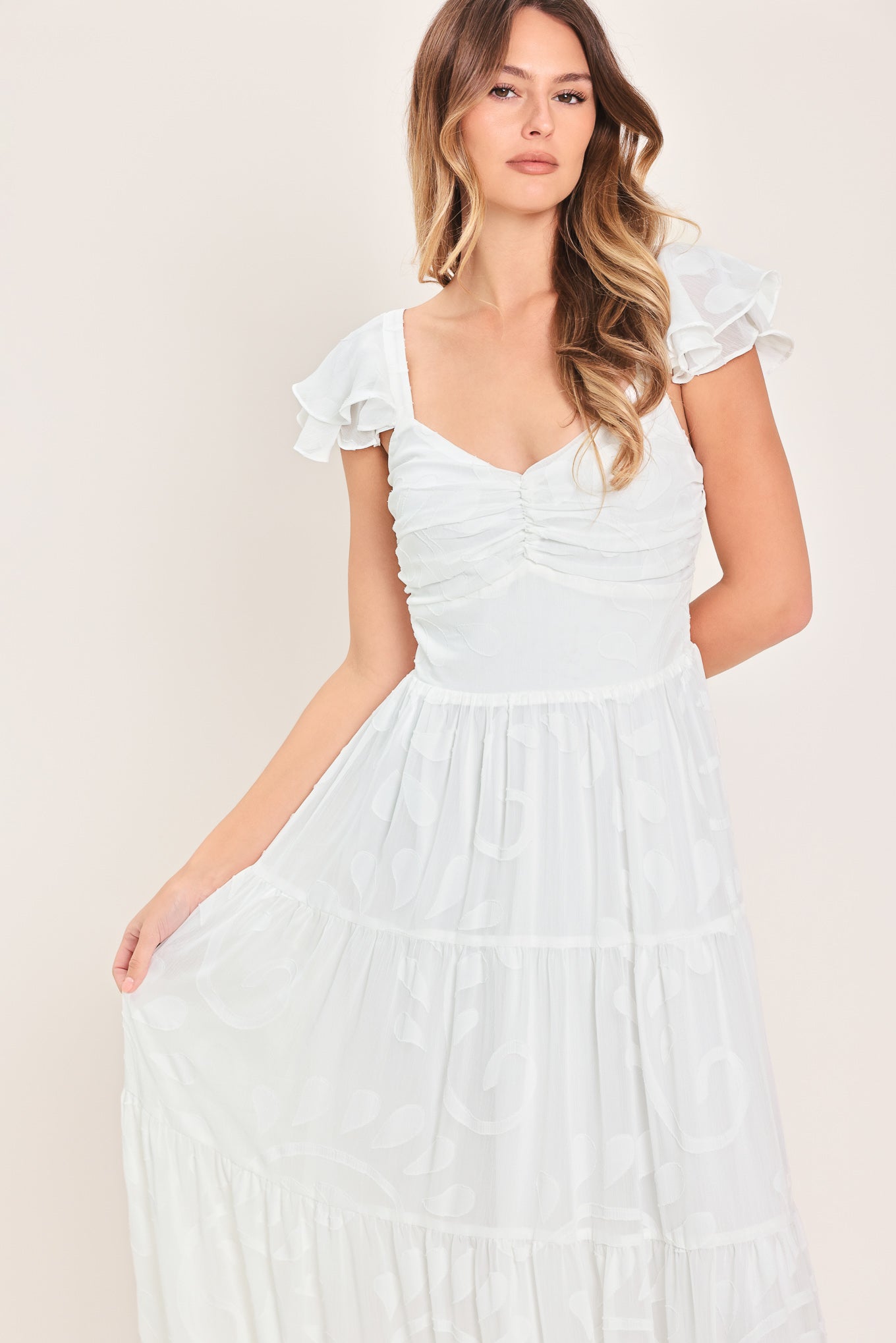Woman wearing a white maxi dress featuring sweetheart neckline, ruffle sleeve, tier skirt and smocked back bodice | FREEMARKET