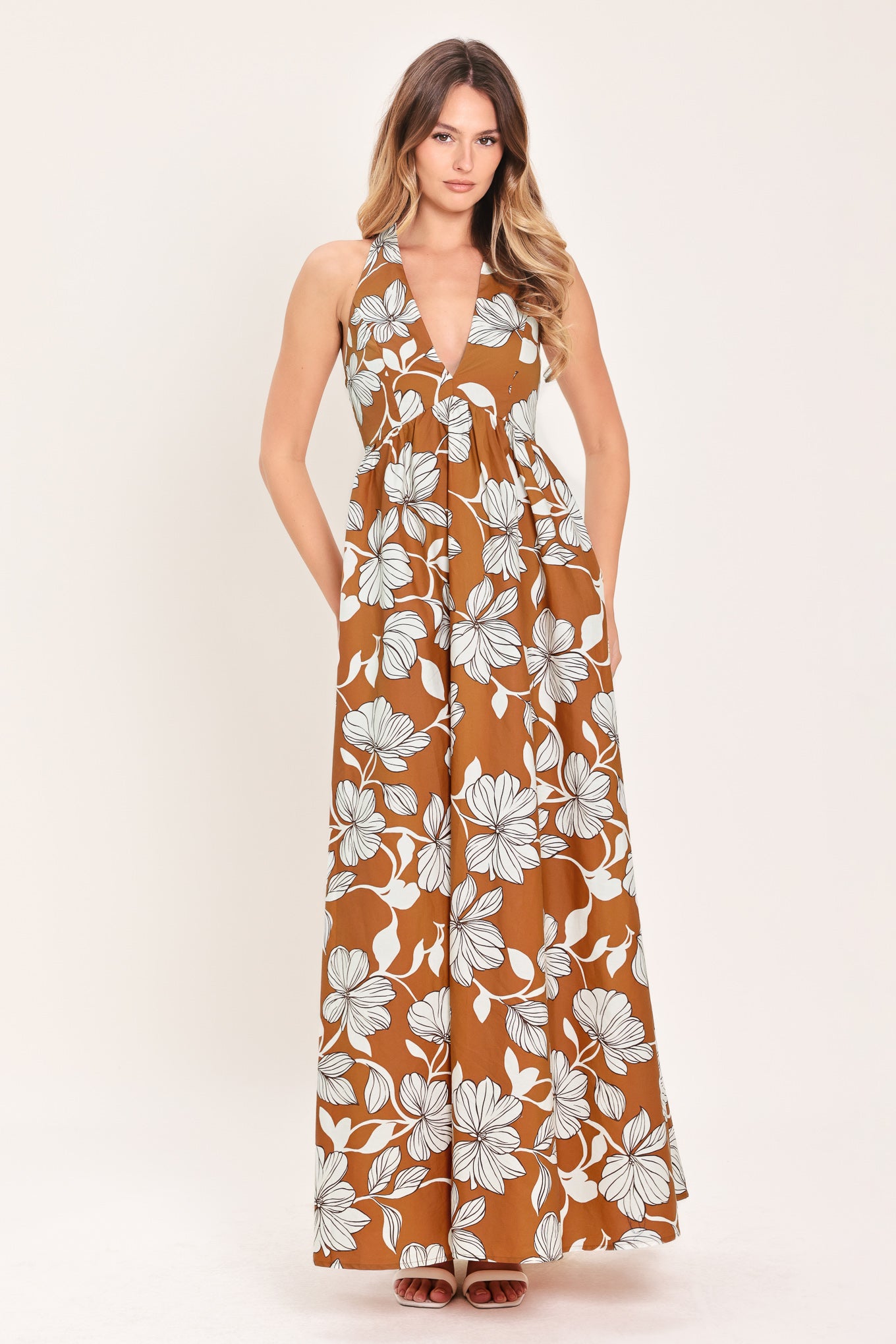 Woman wearing a camel and white with black lineart floral maxi dress maxi dress featuring halter neckline with back neck tie, bare back and smocked bodice | Flying Tomato