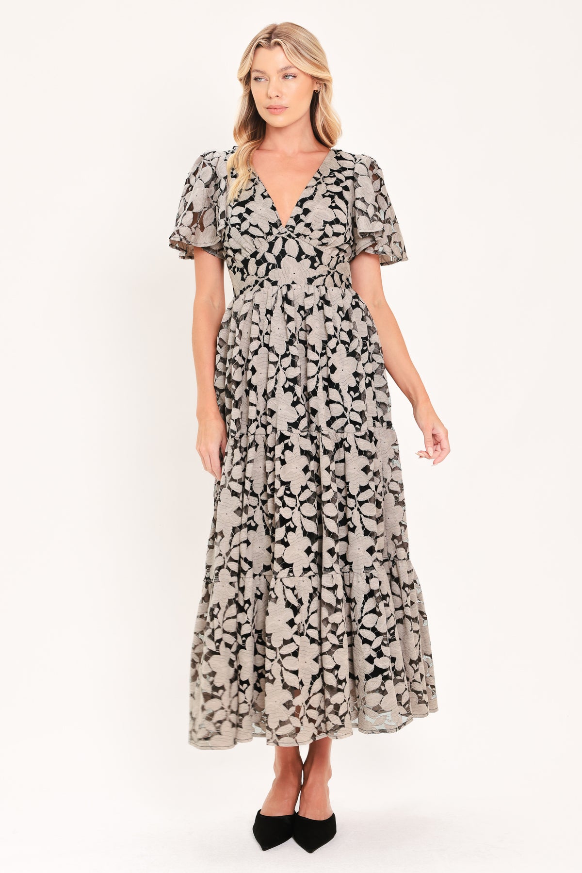 A woman modeling a long-sleeved midi dress with a black and taupe abstract floral pattern | Flying Tomato