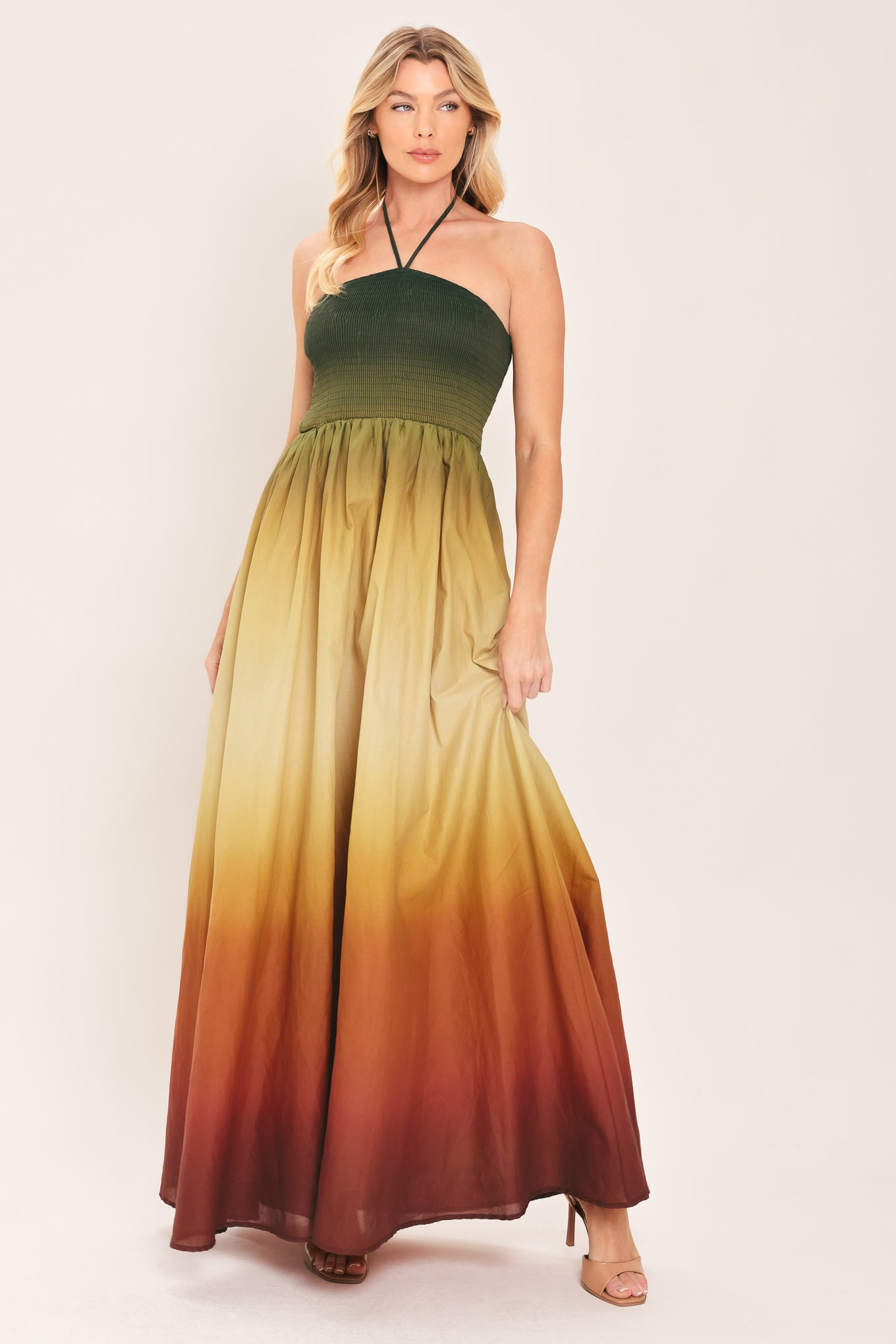 A woman modeling a strapless halter-neck maxi dress with a gradient color-blocked design transitioning from dark green at the bodice to yellow, orange, and brown at the skirt | Flying Tomato