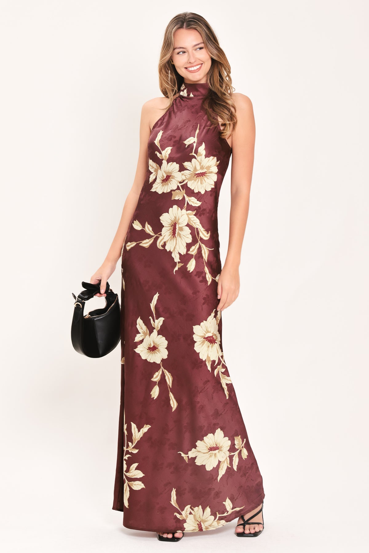 A woman modeling a sleeveless, high-neck floor-length maxi dress in deep burgundy with a cream floral print | FREEMARKET