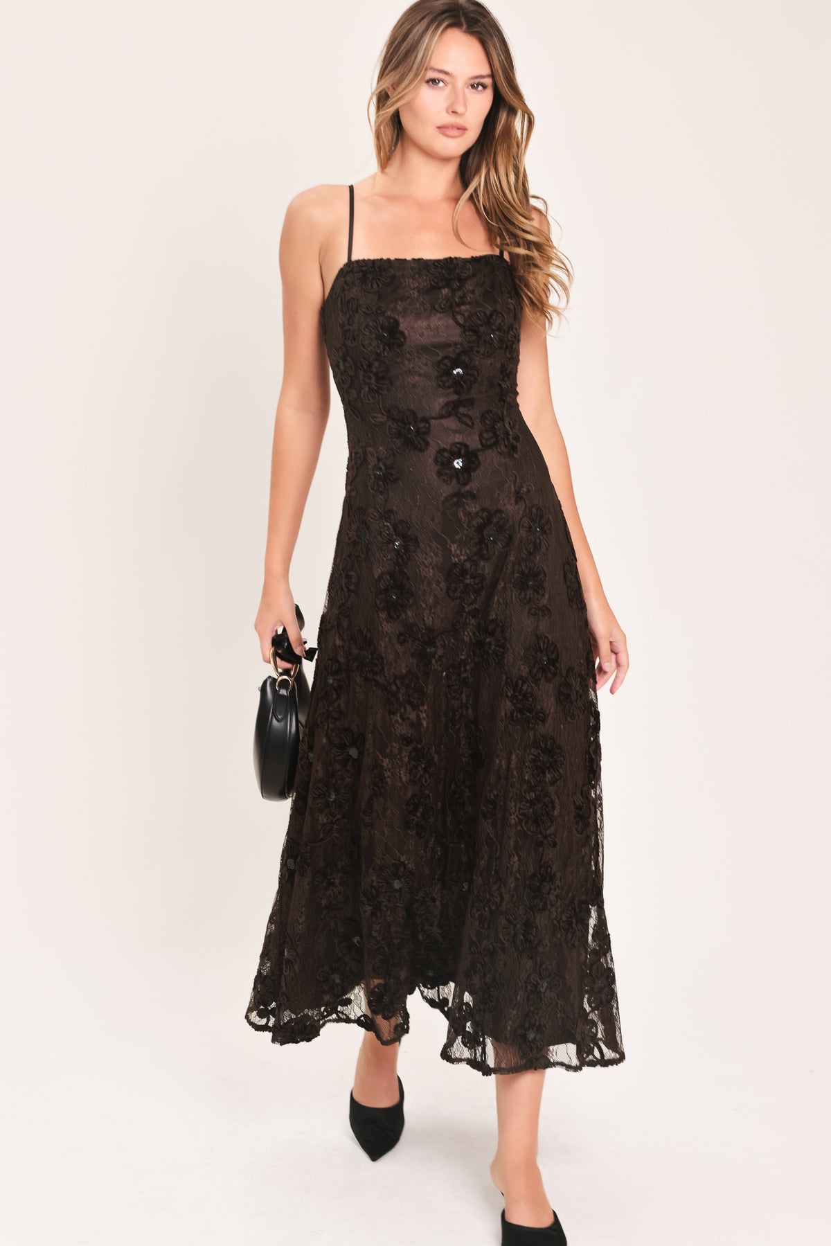 A woman modeling a brown lace midi dress with thin spaghetti straps, a fitted bodice, and a flared skirt | Flying Tomato