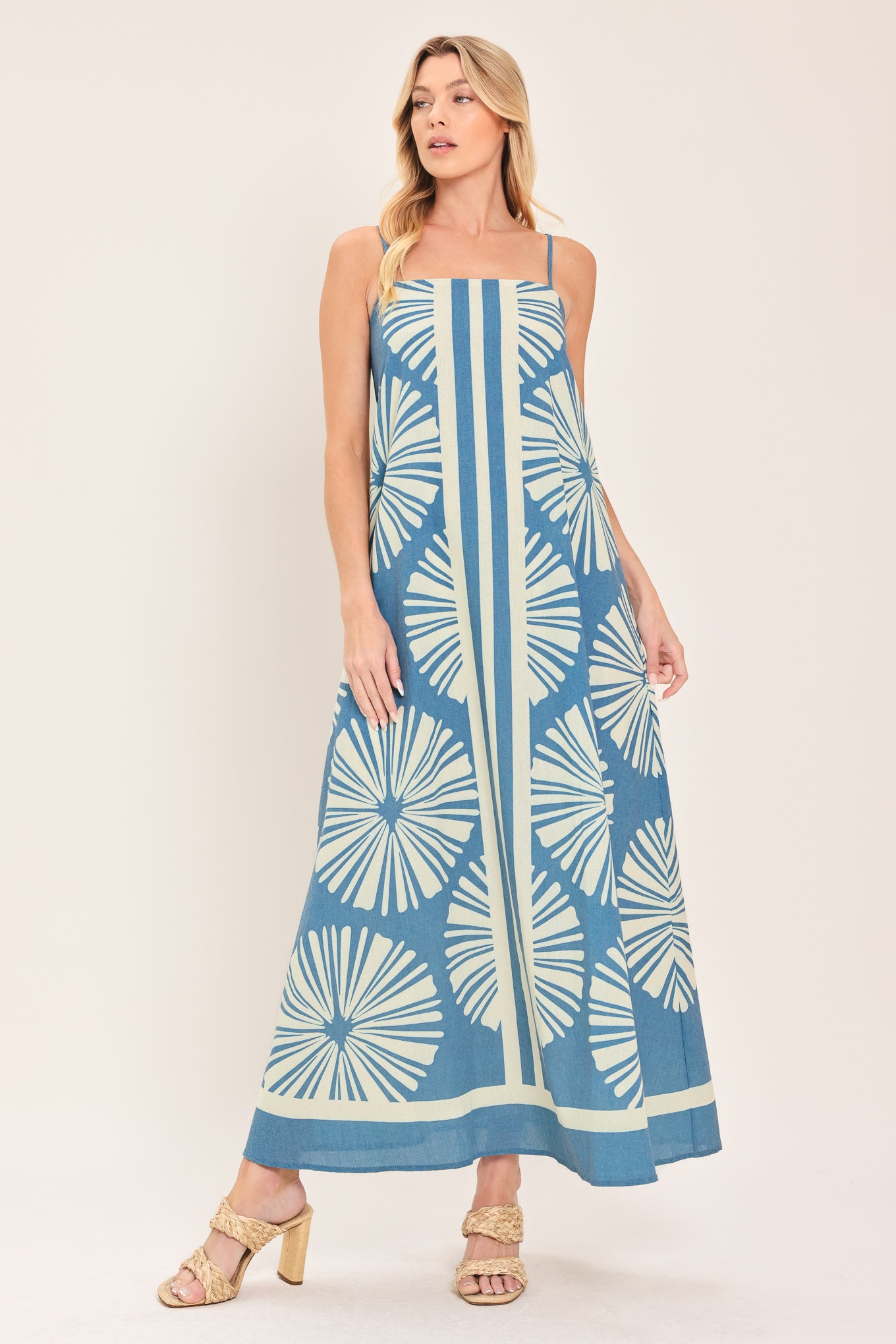 Woman wearing a blue and white patterned maxi dress featuring straight neckline, straps and bare back with zipper closure | Flying Tomato