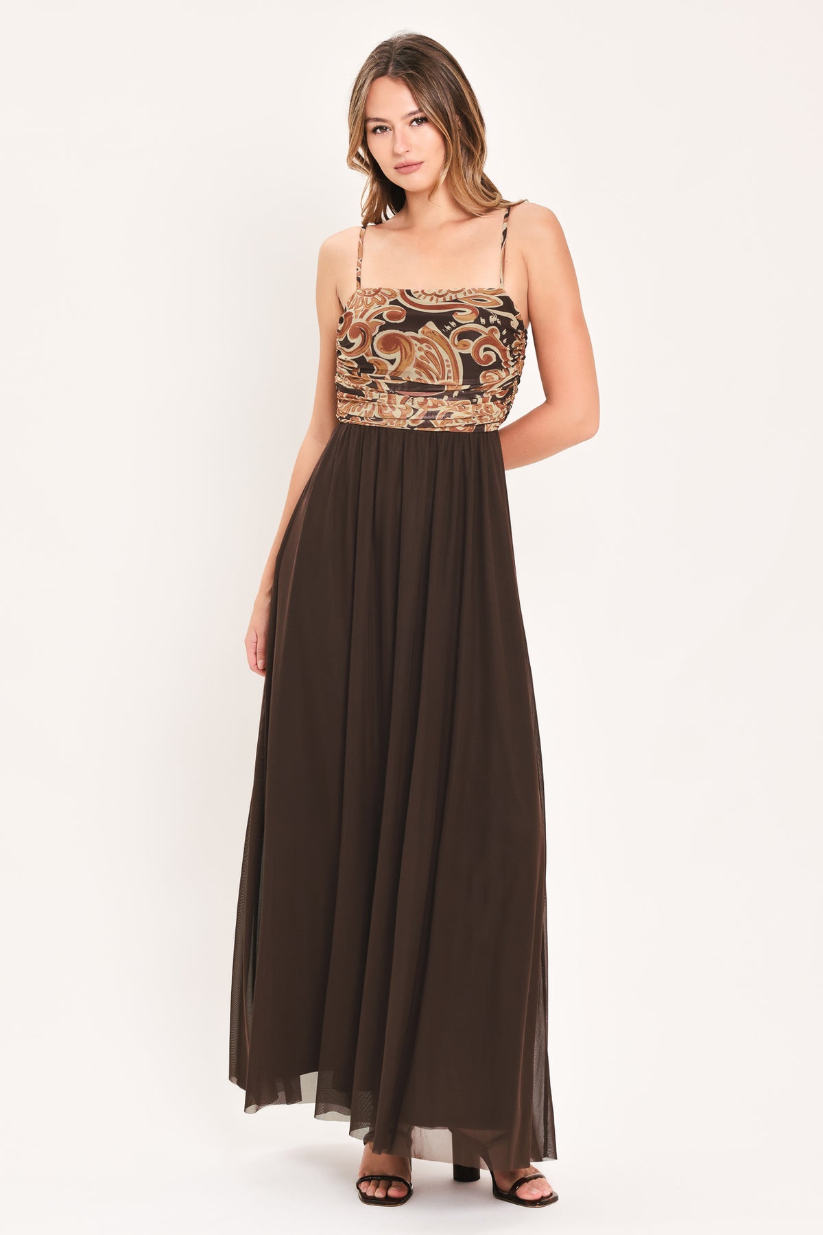 A woman modeling a long brown maxi dress with a patterned bodice and flowing power mesh skirt | Flying Tomato