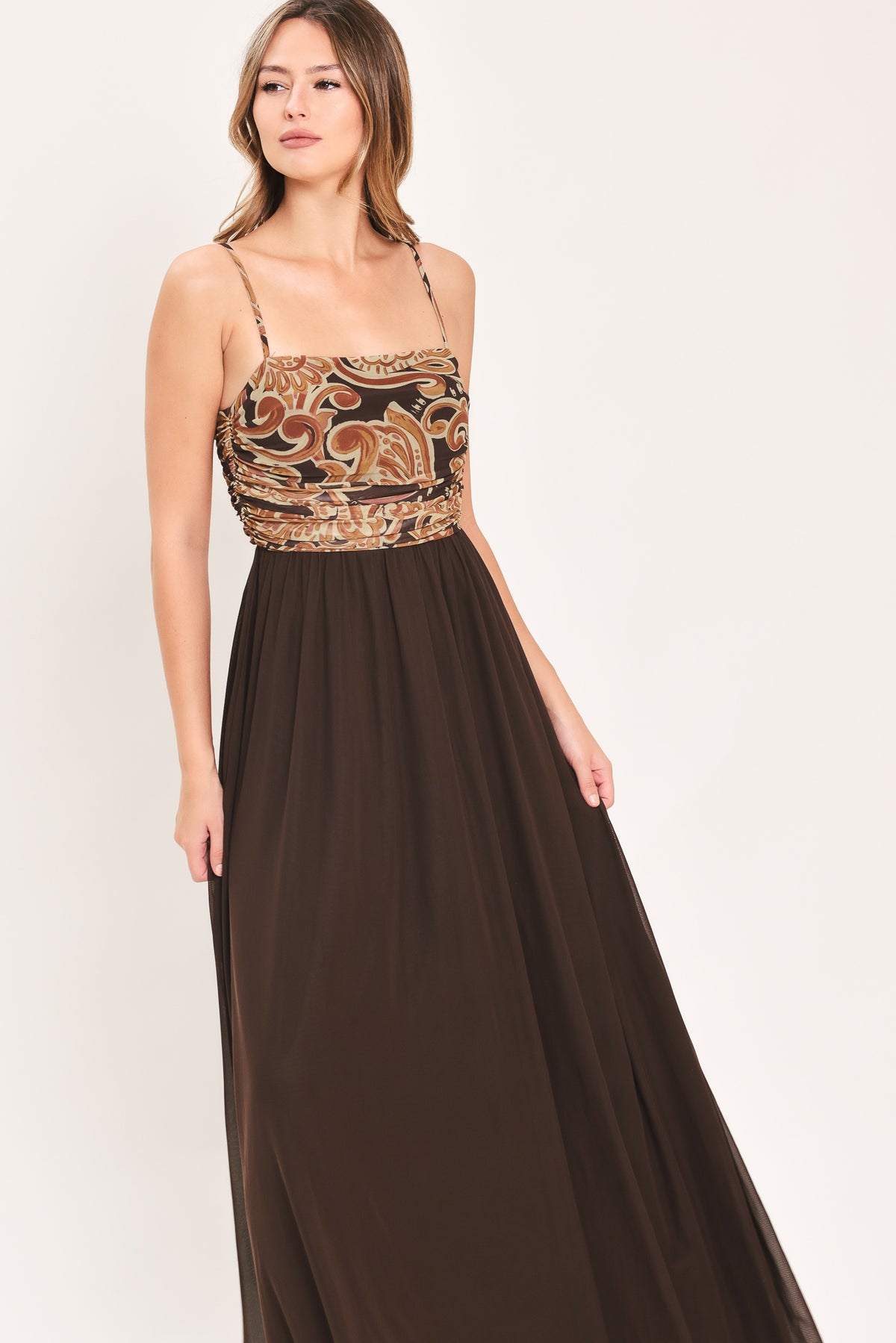 A woman modeling a long brown maxi dress with a patterned bodice and flowing power mesh skirt | Flying Tomato