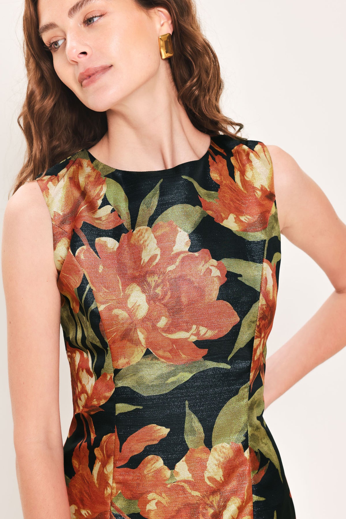 Woman wearing a sleeveless black midi sheath dress with orange flowers and green leaves printed | Flying Tomato